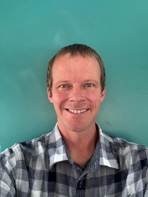 Male therapist in a plaid shirt wears a friendly smile