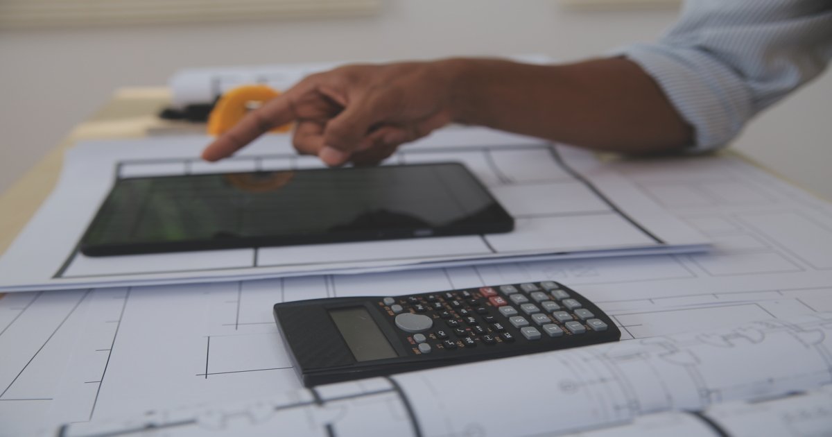 a-man-using-a-tablet-and-calculator-to-plan-a-building-and-cost-estimation
