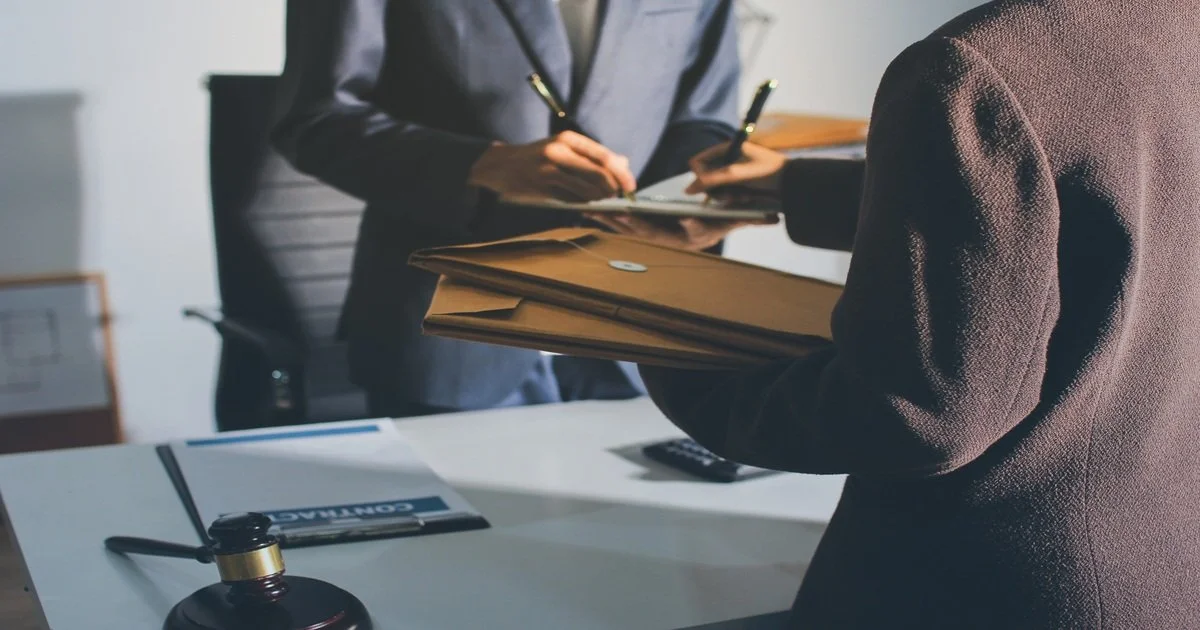 a-man-and-woman-are-standing-at-a-desk-with-a-pen-and-papers