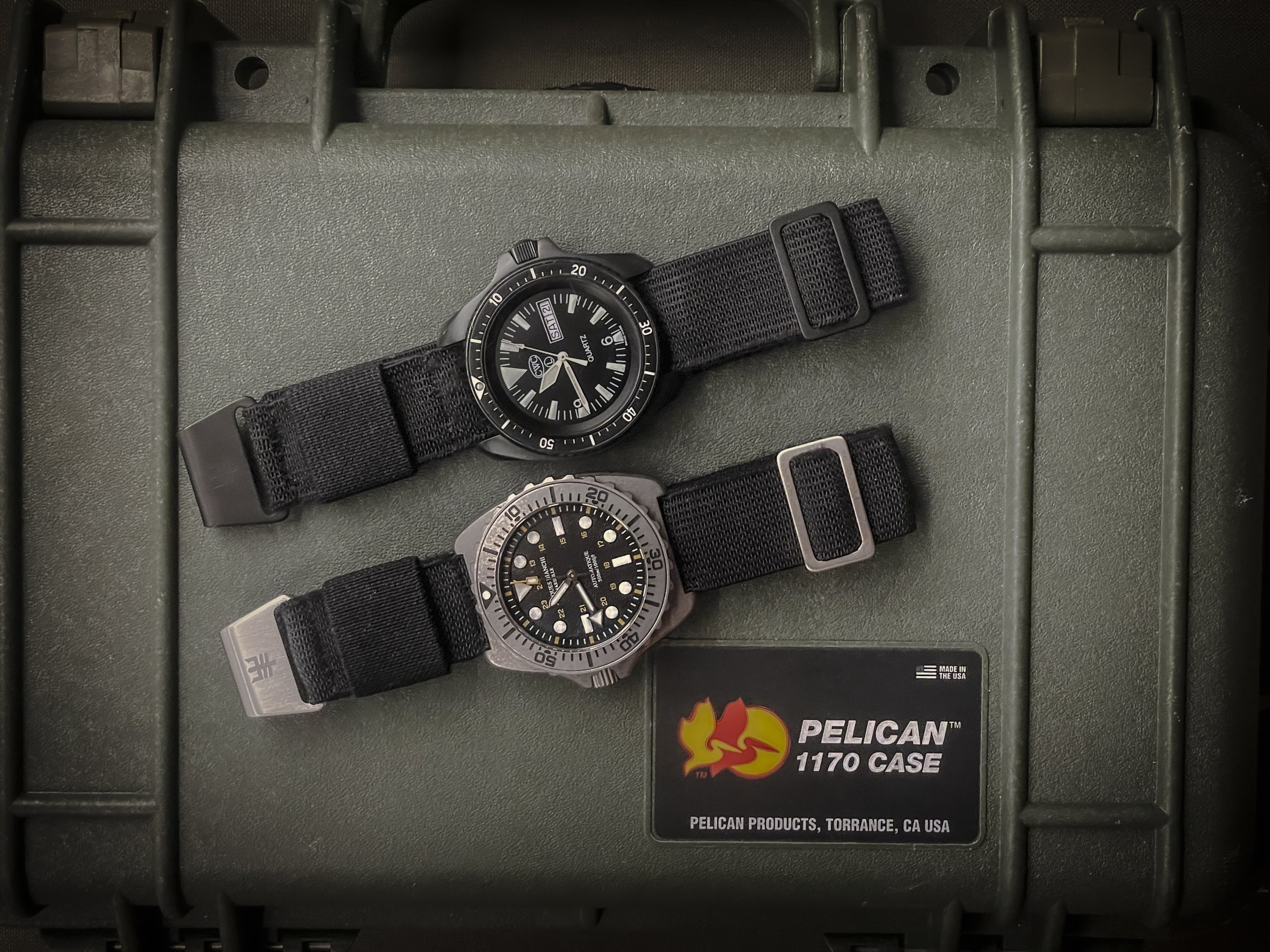 Aquaborne system 21 Riser straps on field watches placed on Pelican case, military-inspired nylon straps designed for rugged use