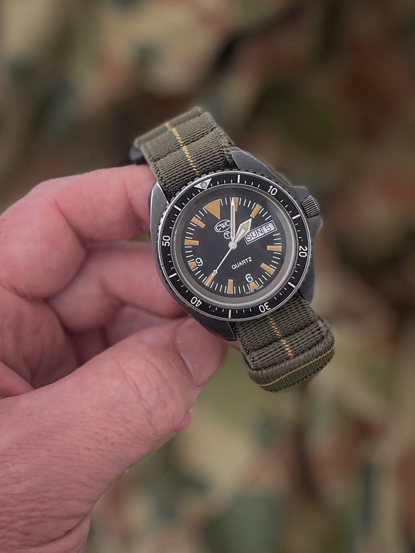 Aquaborne System-21 Breacher strap in recon green with yellow tracer fitted to a dive watch, held outdoors in natural light