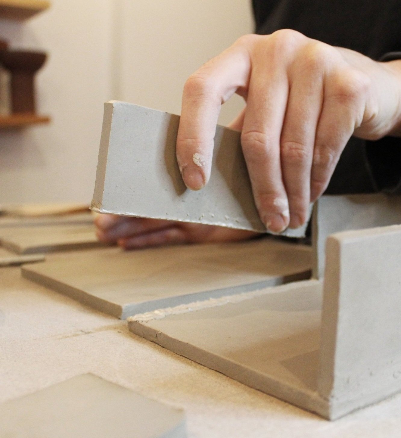 Close-up of hand slab-building with clay, demonstrating a pottery technique at Loam in Moabit, Berlin.
