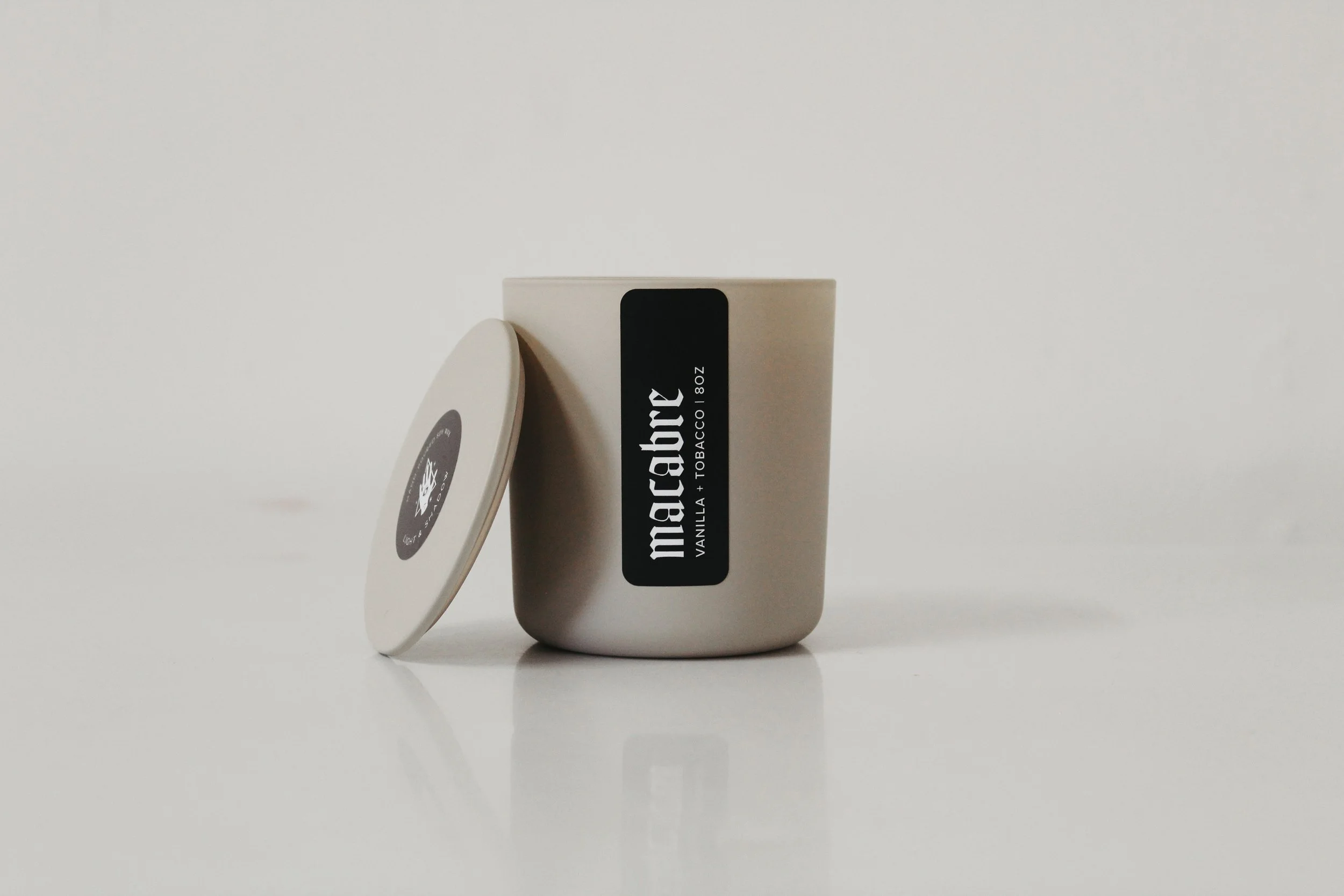 White container with a black label reading 'Macabre Vanilla + Tobacco 8oz' and a matching round lid with a black and white label.