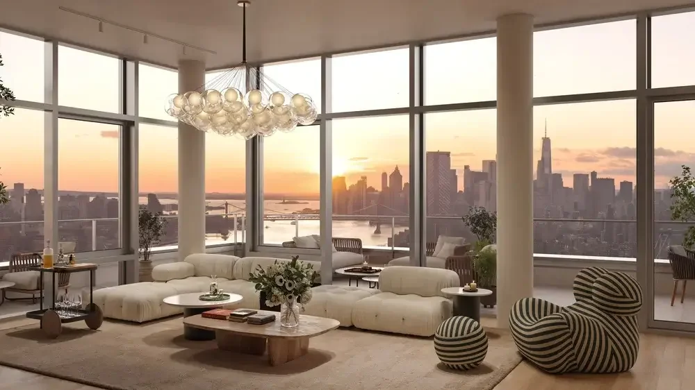 Living room with large windows overlooking a cityscape at sunset, featuring a modern chandelier, beige sectional sofa, striped lounge chair, and various decorative plants and furniture.
