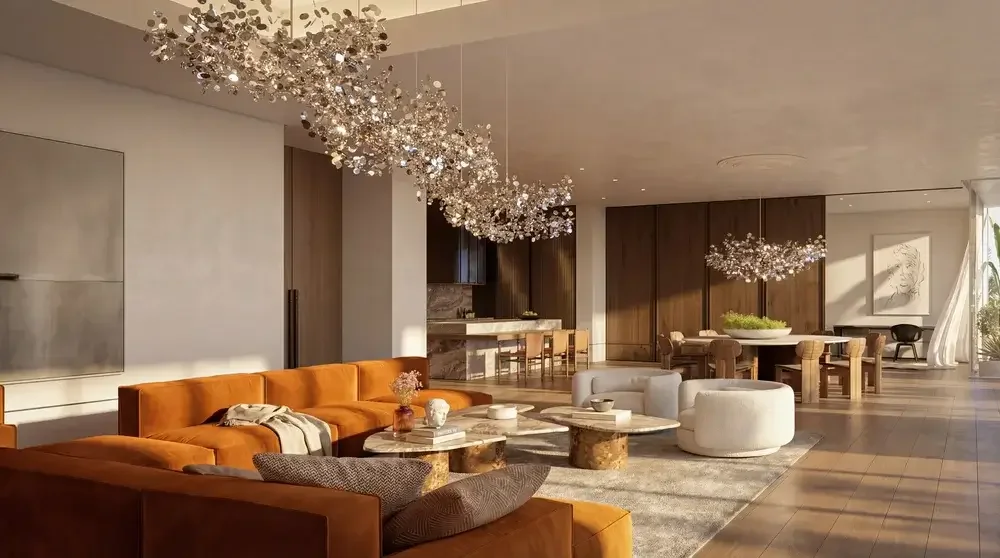Luxurious living room with orange and white sofas, marble coffee tables, modern chandeliers, and wooden accents, in a spacious open floor plan.