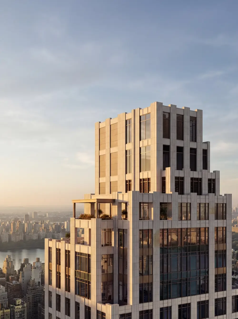 High-rise building with modern architectural design in an urban area during sunset, with a cityscape and river in the background.