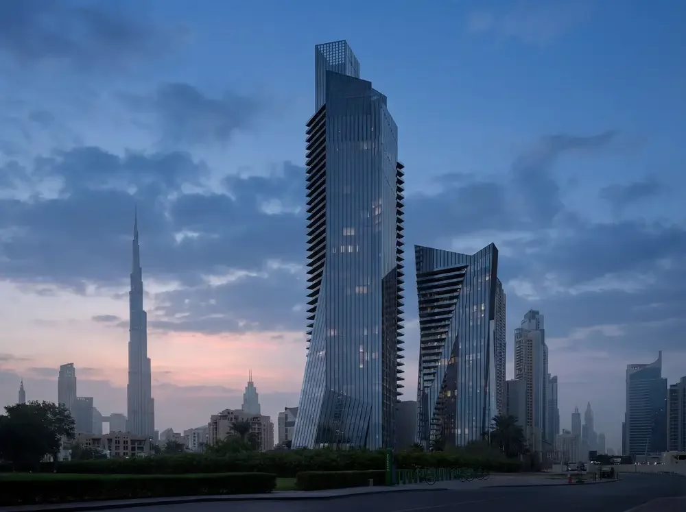 Cityscape at dusk featuring modern skyscrapers, including the Burj Khalifa in Dubai, with a cloudy sky in the background.