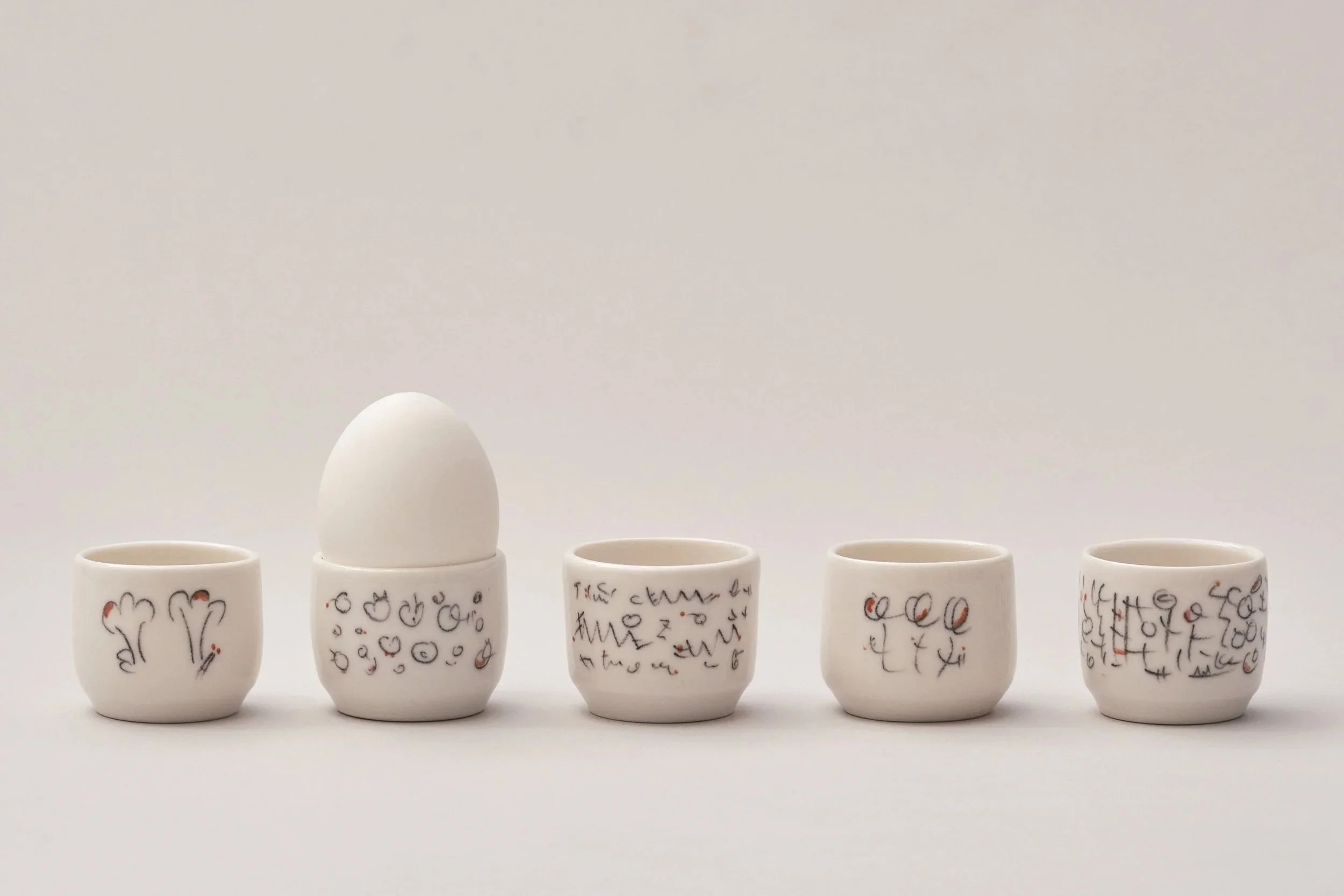 A row of hand decorated thrown porcelain egg cups
