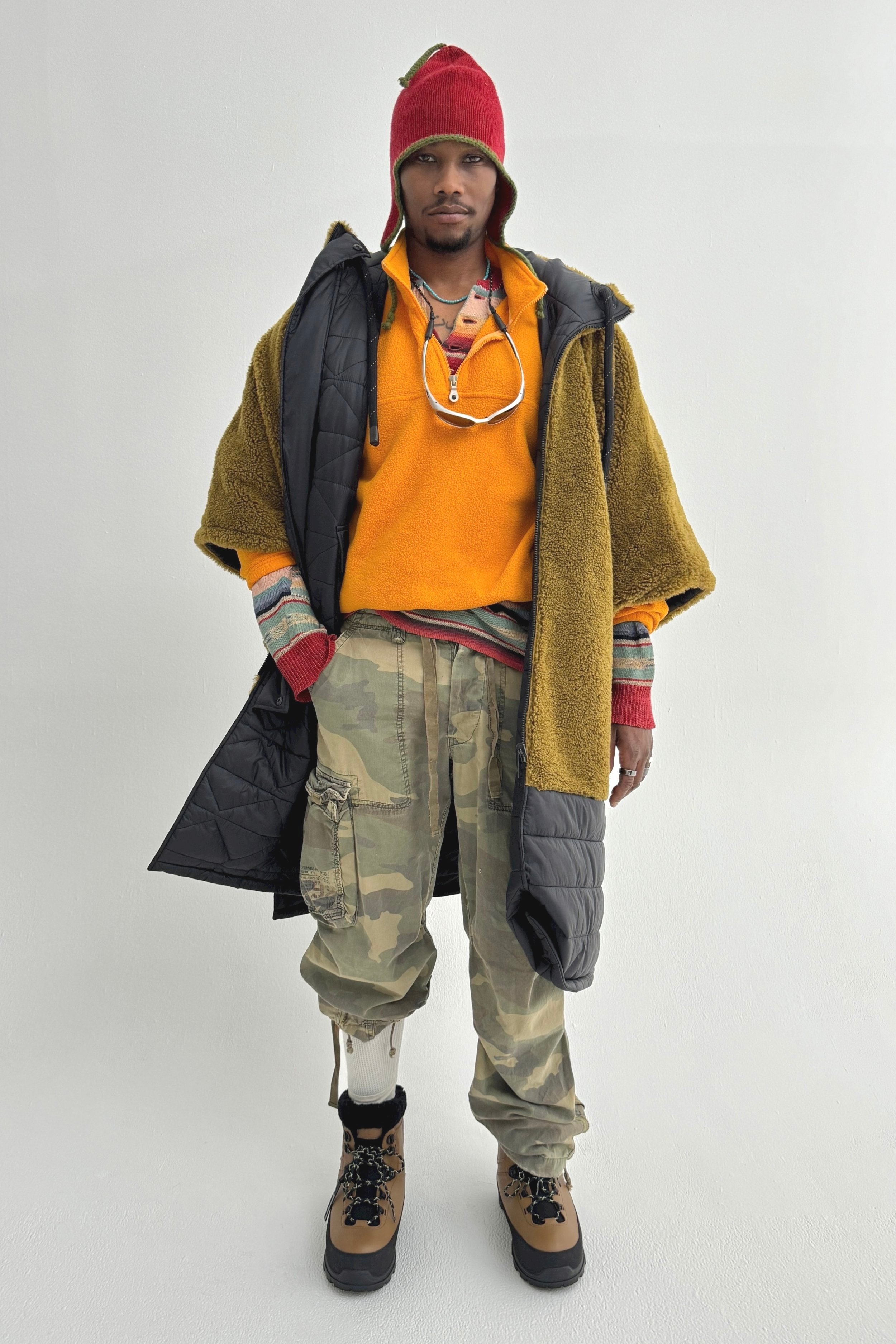A man dressed in outdoor winter and hiking gear standing against a plain white background.