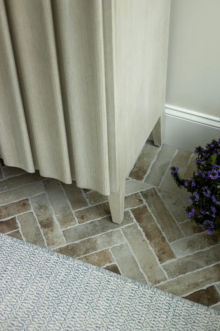 A close-up detail of a thoughtfully designed sunroom, highlighting the craftsmanship, materials, and textures that contribute to the space’s refined aesthetic. The focal point is the base of a custom fluted console cabinet finished in a light natural
