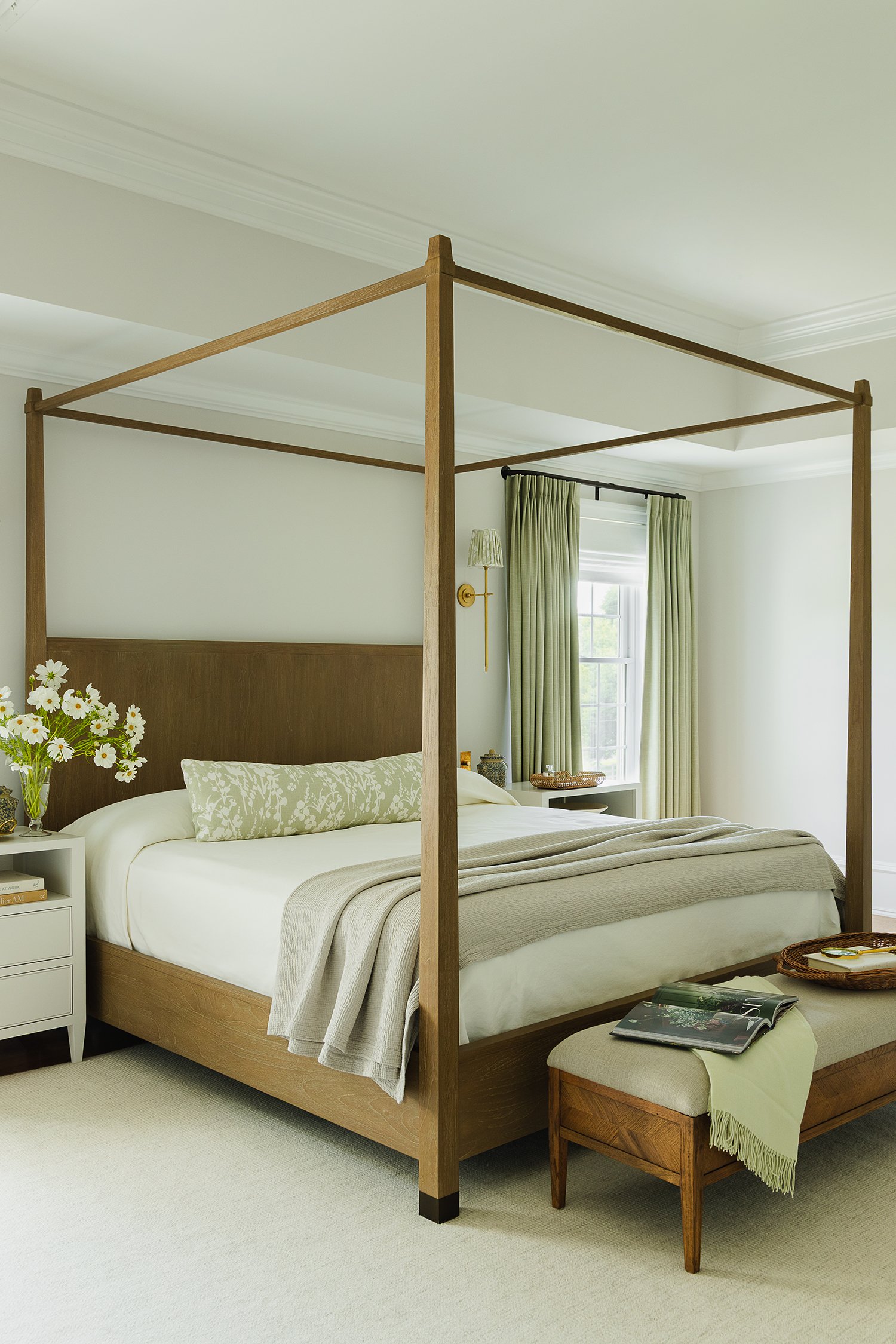 Full view of a luxury primary bedroom featuring a custom walnut canopy bed, tailored drapery, layered neutral bedding, upholstered bench, custom nightstands, and timeless interior design by Kate Kelly Interiors.