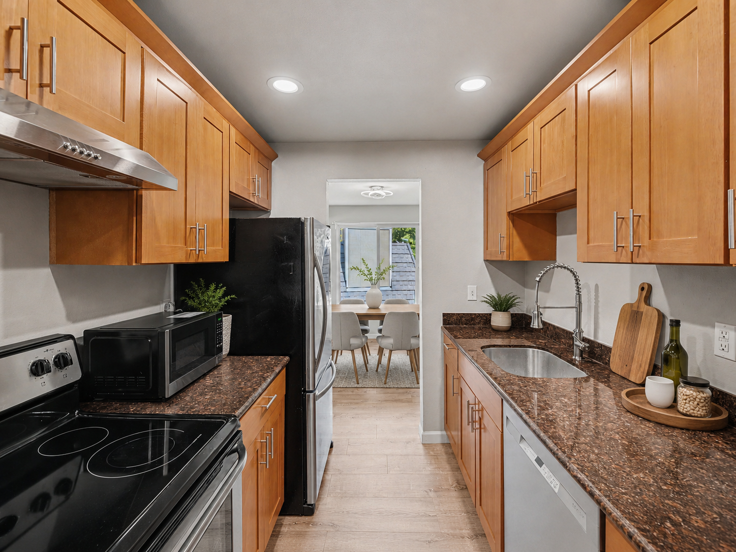 Beautiful kitchen with stainless steel appliances and sleek counters steps from the dining area virtually staged 