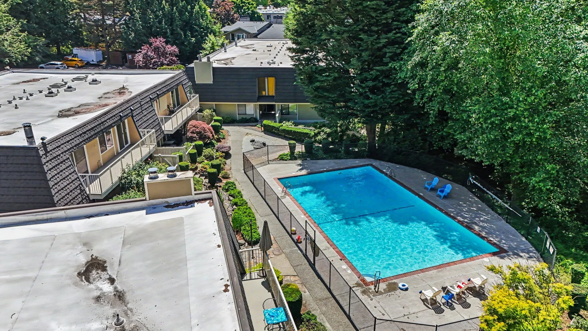View of sparkling pool, outdoor lounge area, greenbelt and condo to the top left