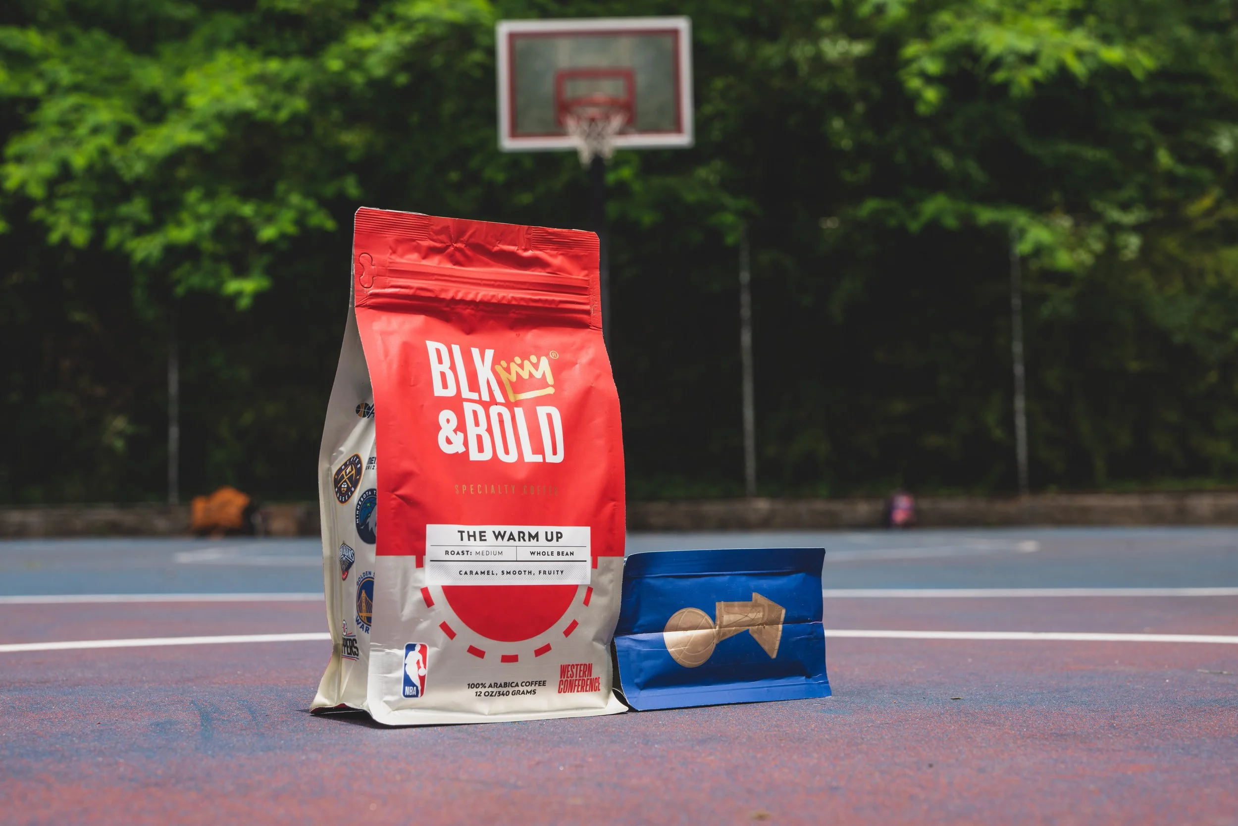 Coffee bags on an outdoor basketball court with hoop in background.