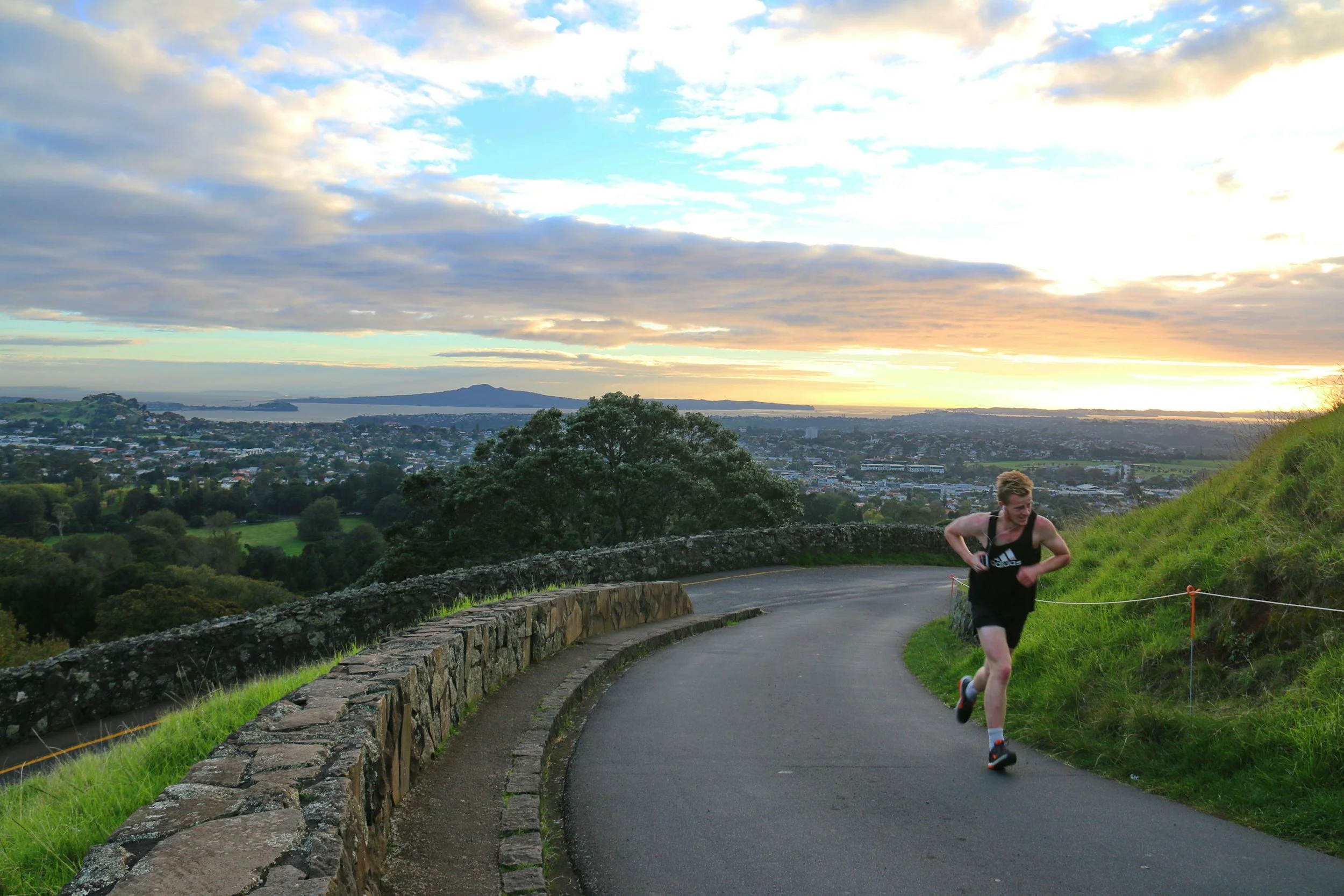 Runner in a black singlet running up mount eden path in early morning light