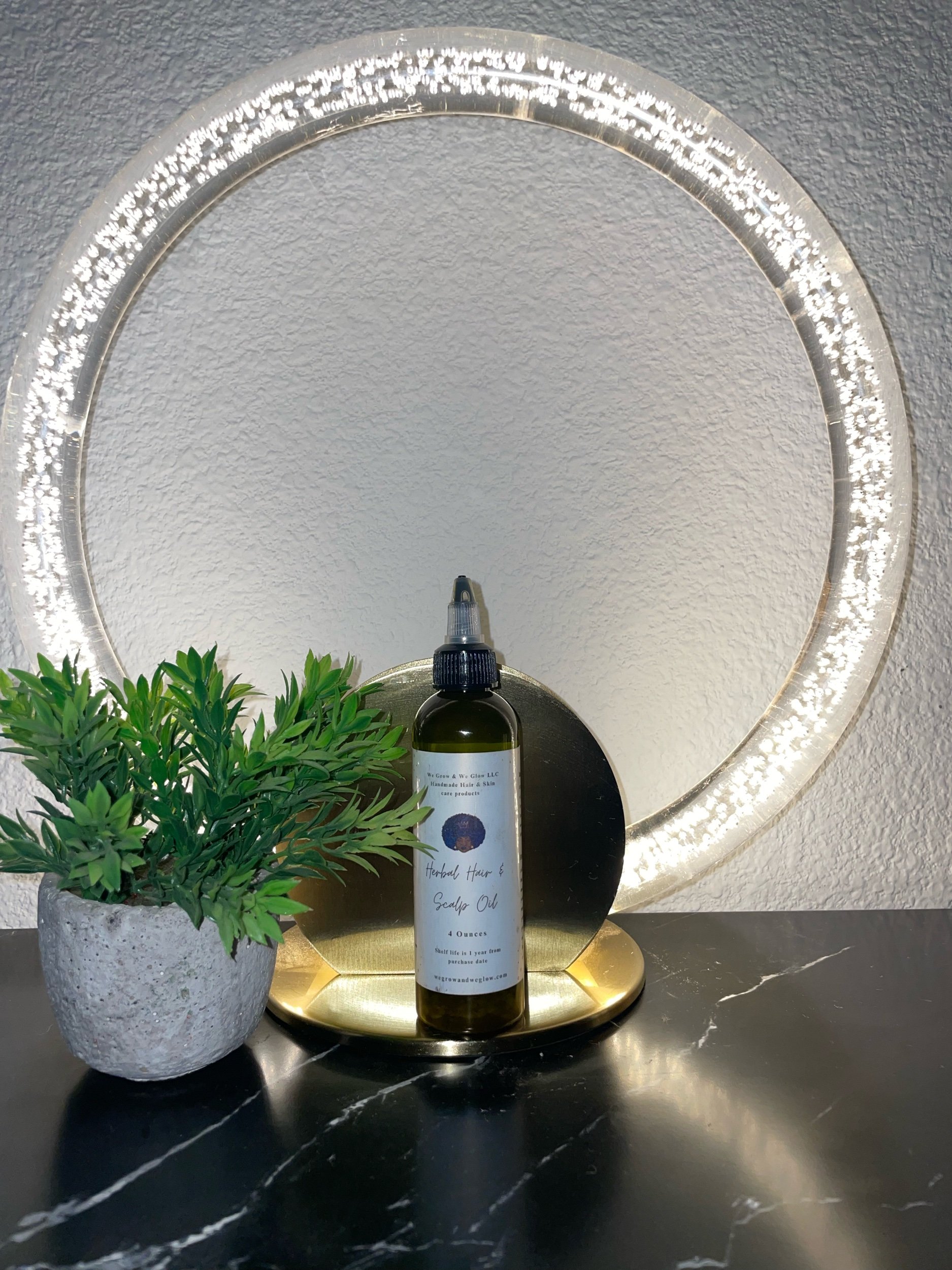 A row of bottles labeled herbal hair and scalp oil on a black wooden surface.