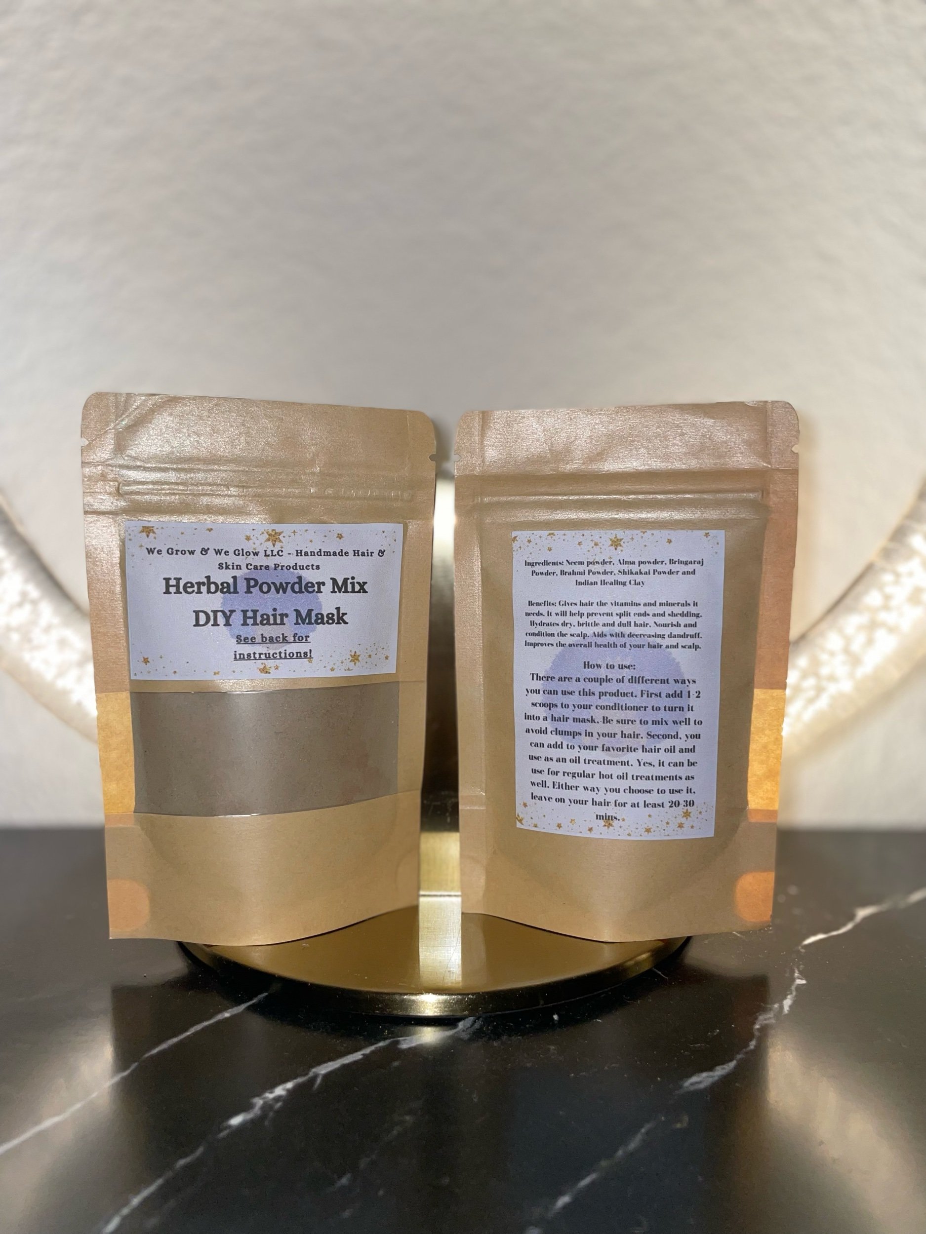 A package of herbal powder mix for a DIY hair mask next to an empty glass jar with a metal lid on a white surface.
