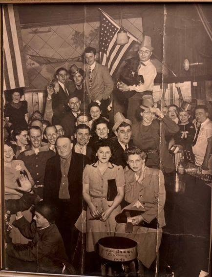 The second annual VE Day celebration in 1946 at Ernie's Bleachers Bar (now Murphy's Bleachers) across from Wrigley Field. The owner, Ernie Pareti, is holding his dog, Boots. His wife, Margaret Pareti, is below him in the hat.