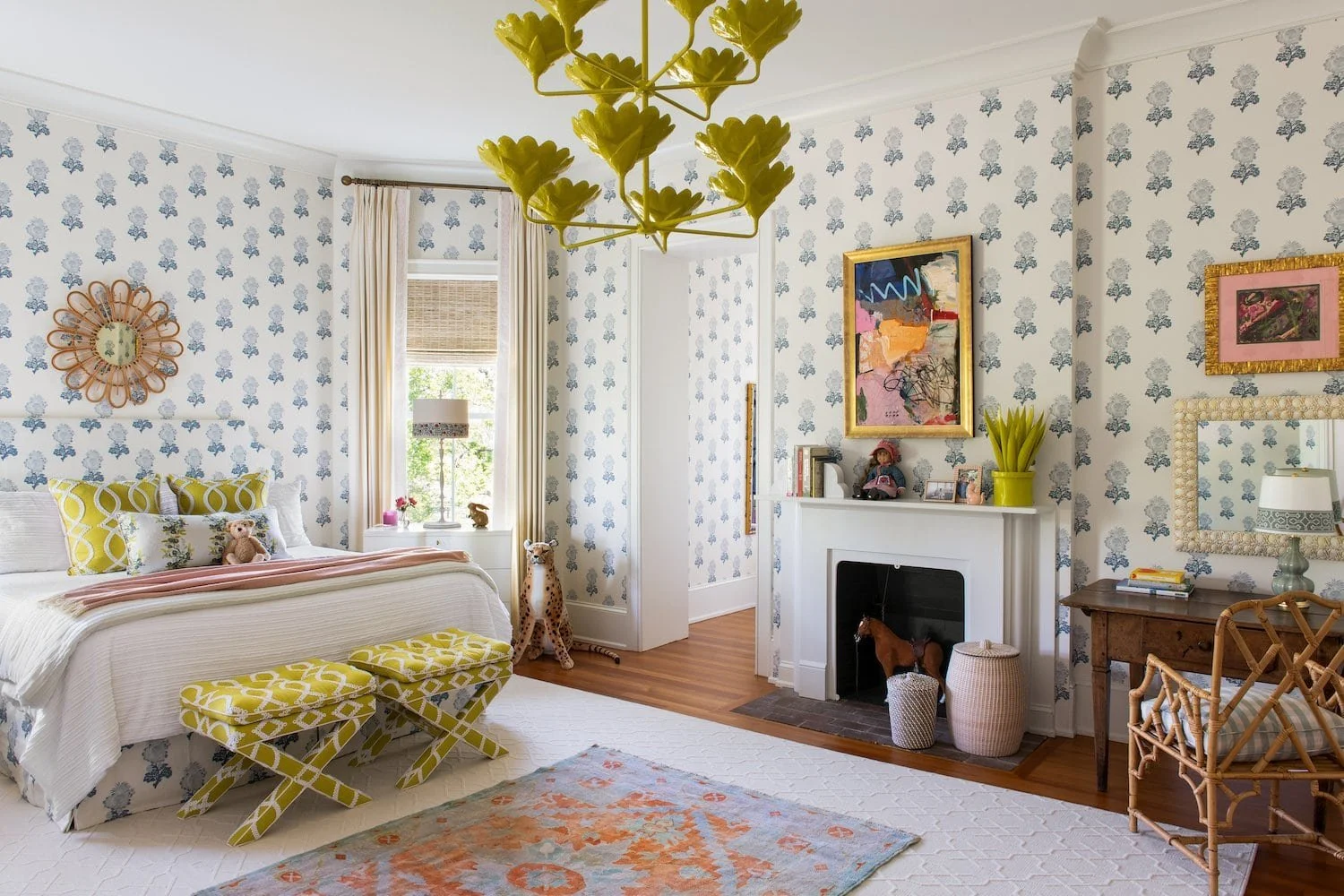 Grand Millennial style bedroom designed by Isabel Ladd Interiors featuring floral wallpaper, vintage-inspired decor, layered textiles, a yellow botanical chandelier, and eclectic artwork.