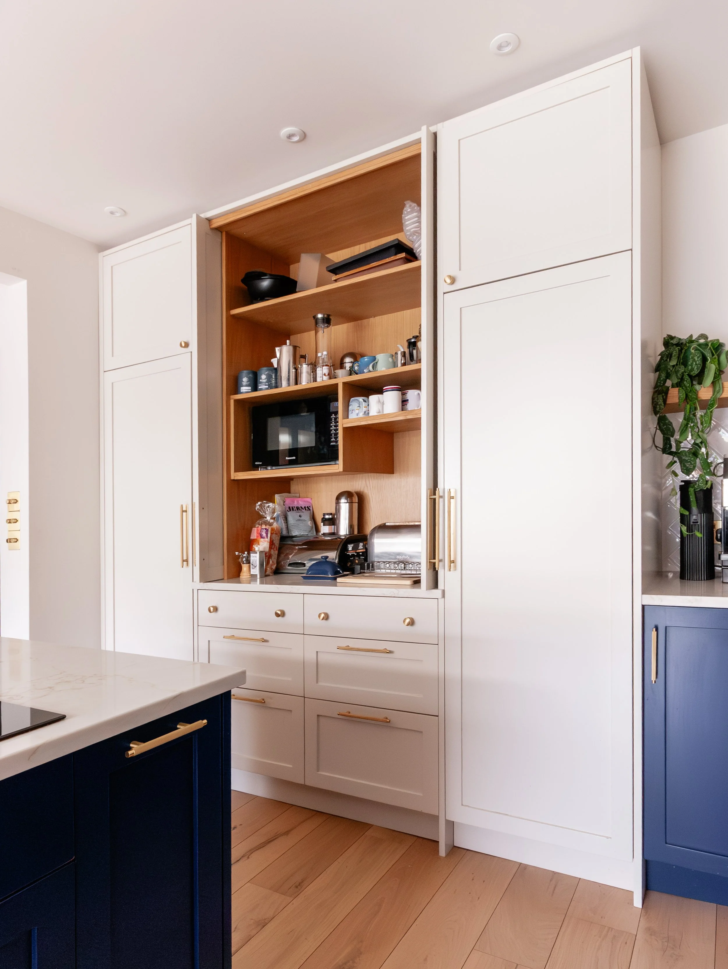 Kitchen storage in Beckenham with concealed appliance cupboard, open shelving and organised everyday items.