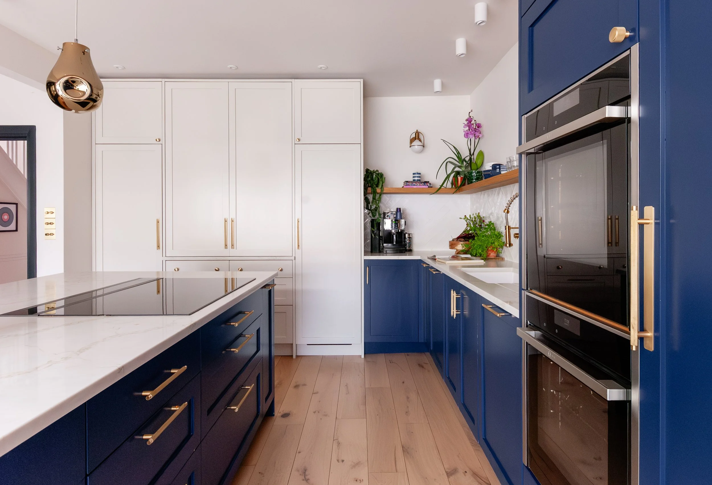 Blue and white bespoke kitchen in Beckenham with island, integrated ovens and oak flooring