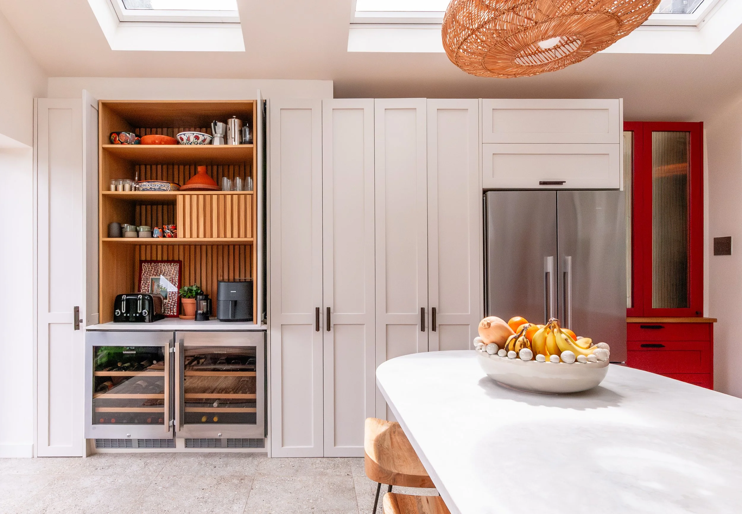 Bespoke storage wall in a Forest Hill kitchen extension, with breakfast cupboard, wine fridges, American-style fridge freezer, red reeded glass larder and curved island