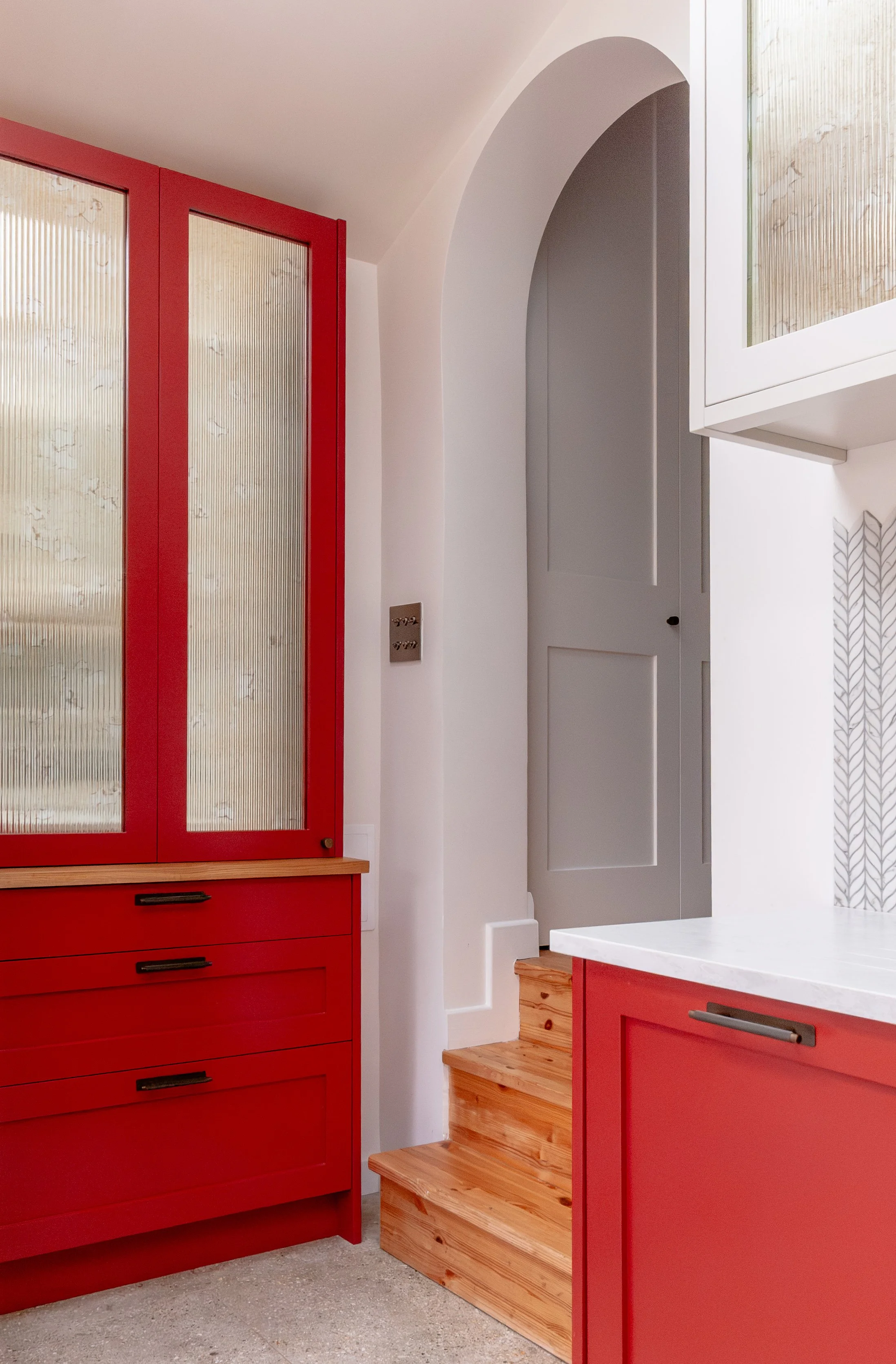 Red larder with antique reeded mirror fronts in a Forest Hill kitchen extension, beside the original arched opening and internal steps
