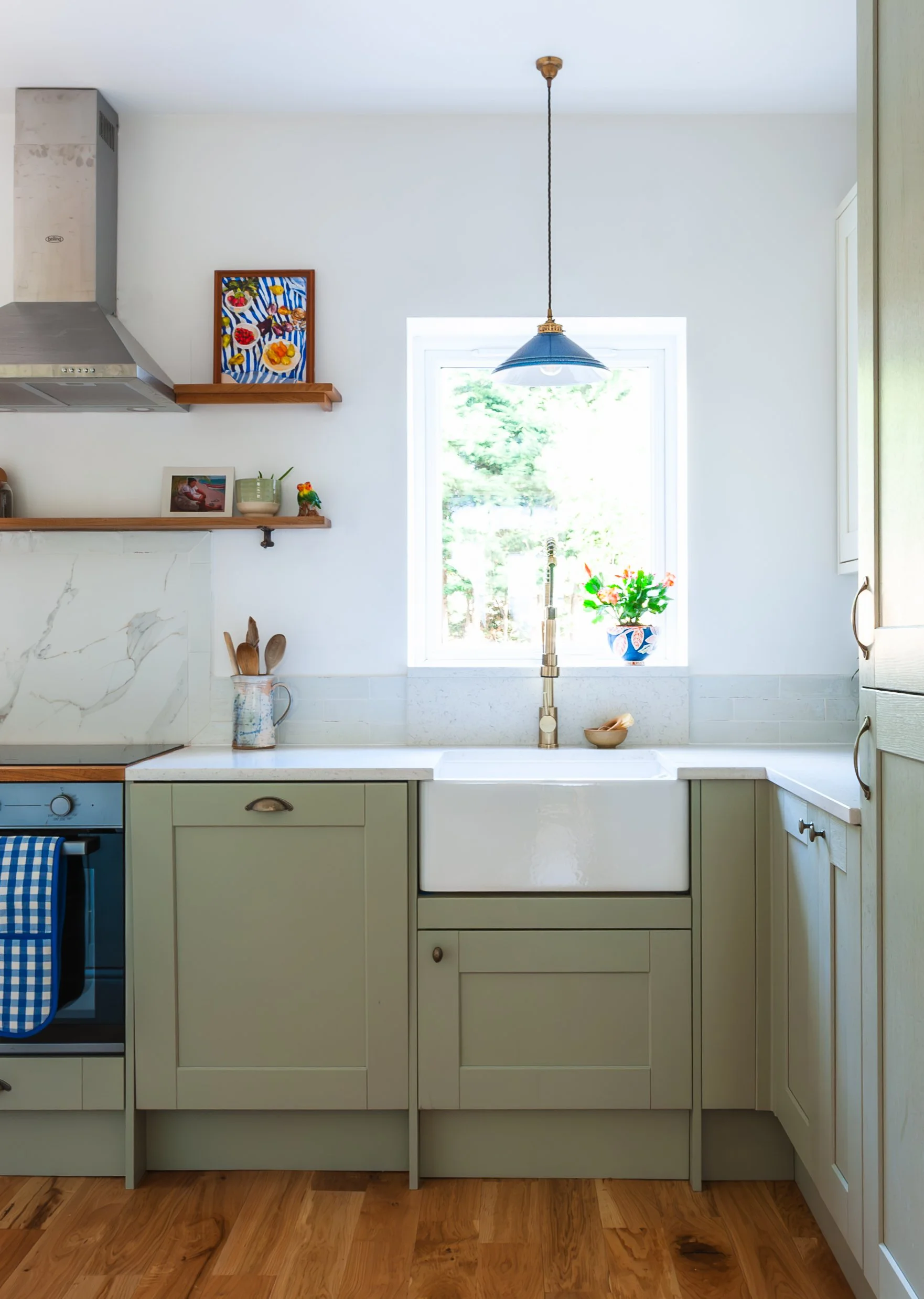 Kitchen in Ladywell with farmhouse sink, open shelving, pendant light, artwork and personal decorative details.