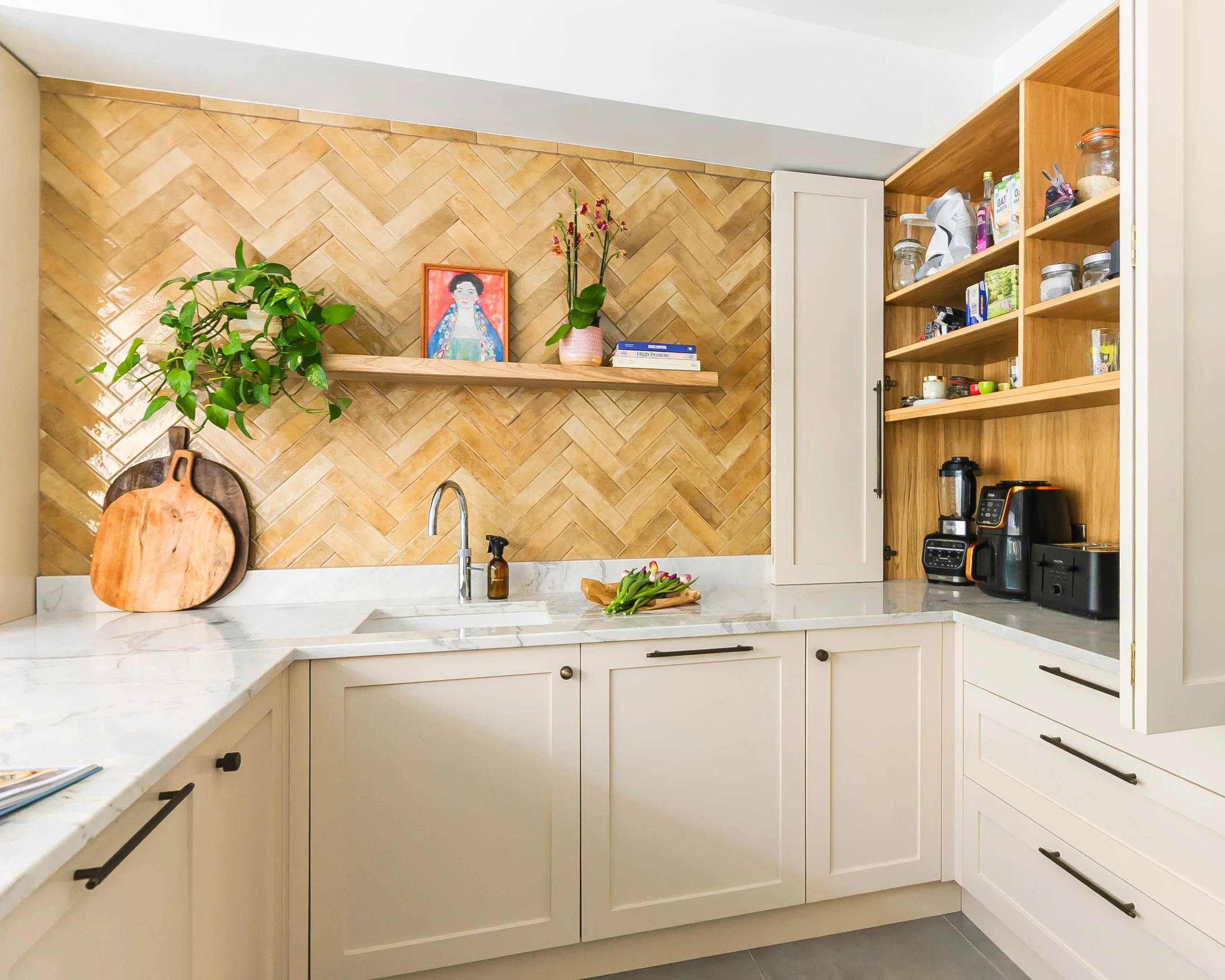 Bespoke kitchen in Forest Hill with bi-fold cupboard doors to concealed appliance store and workspace with open shelving, integrated storage and warm oak timber details.