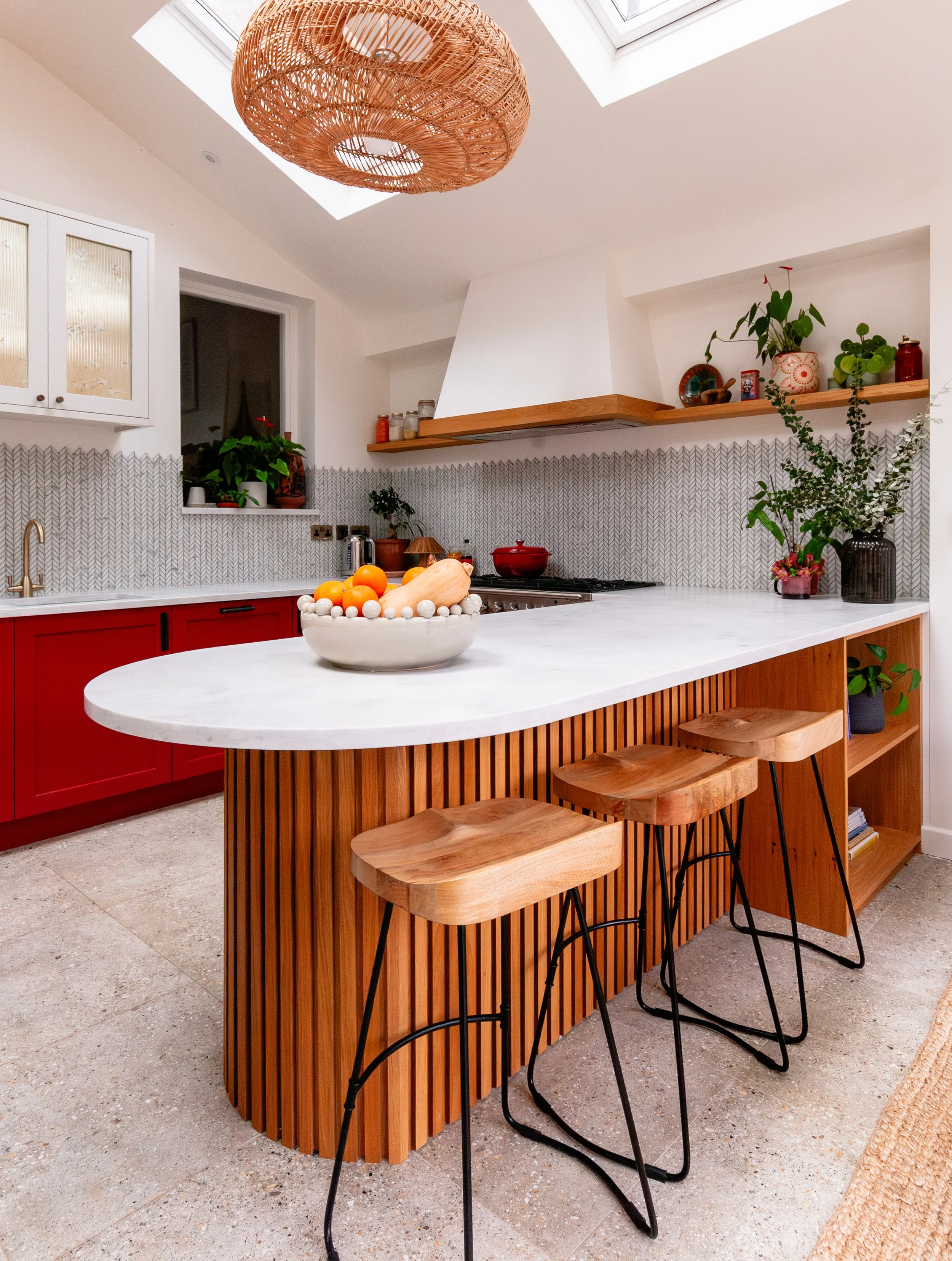 Light-filled Forest Hill kitchen extension with a curved oak peninsula, sociable seating and bespoke red cabinetry designed for entertaining
