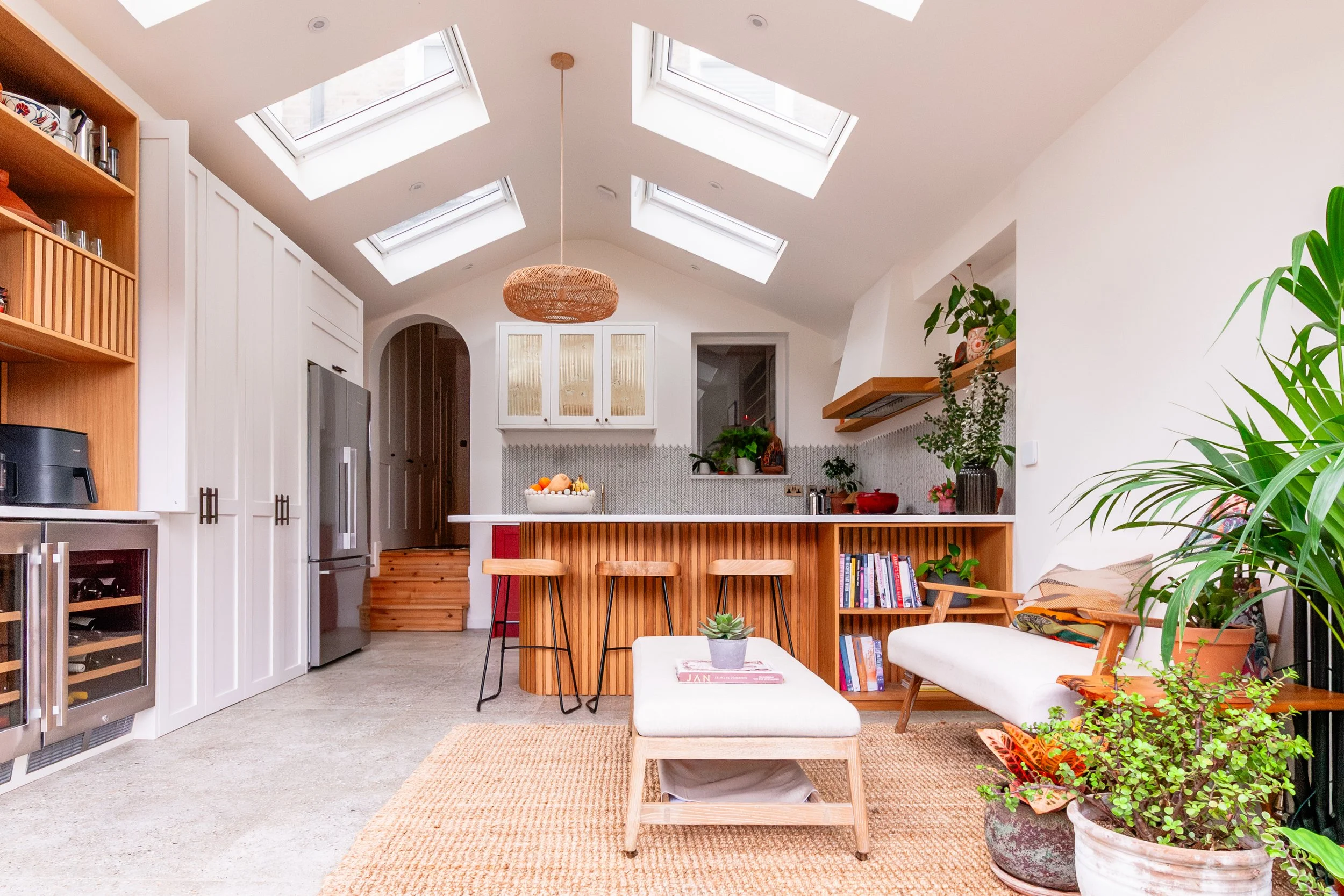 Red and oak kitchen extension in Forest Hill with curved peninsula seating, rooflights and a relaxed garden-facing seating area