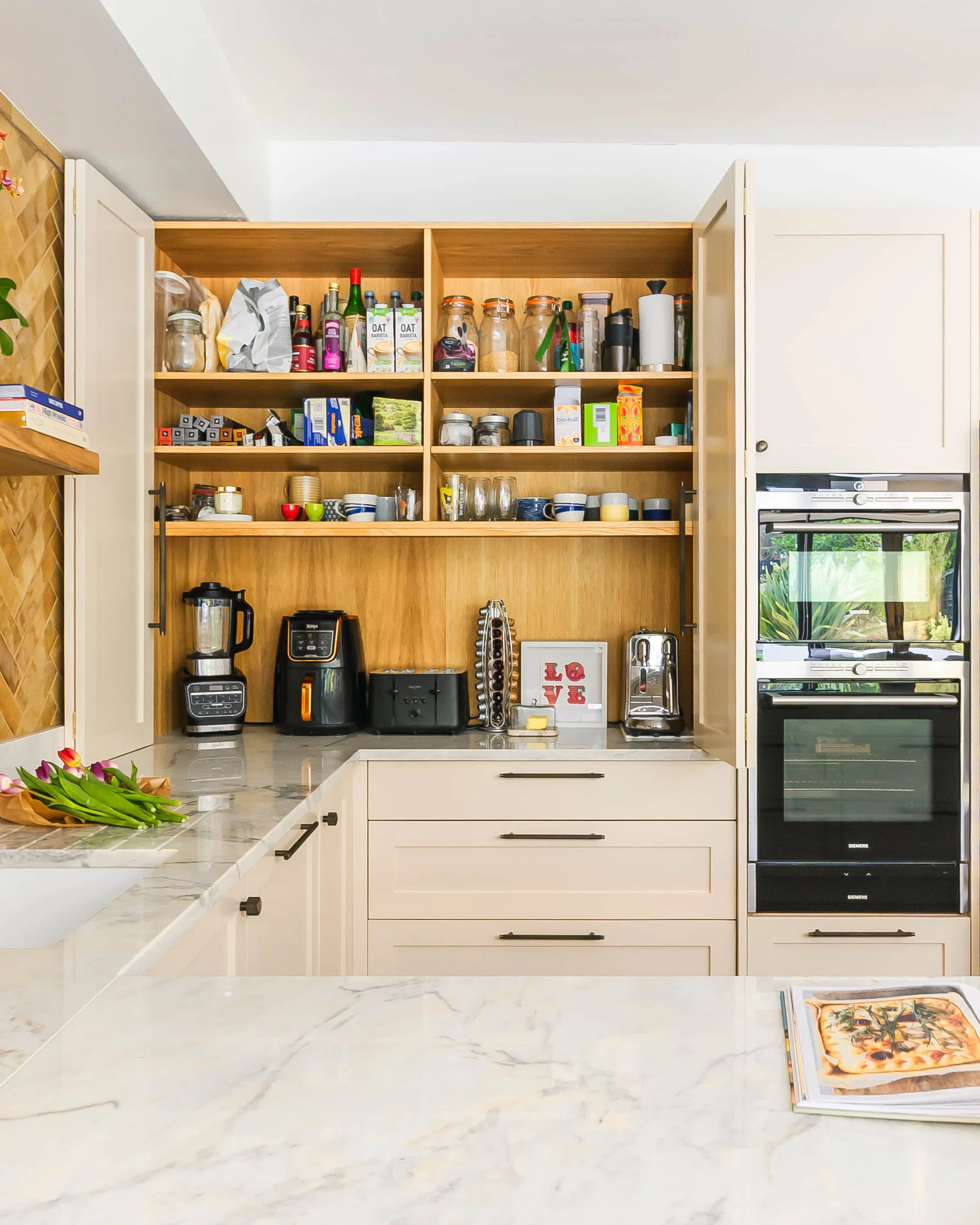 Kitchen storage in Forest Hill with open appliance cupboard, organised pantry shelves and integrated ovens.