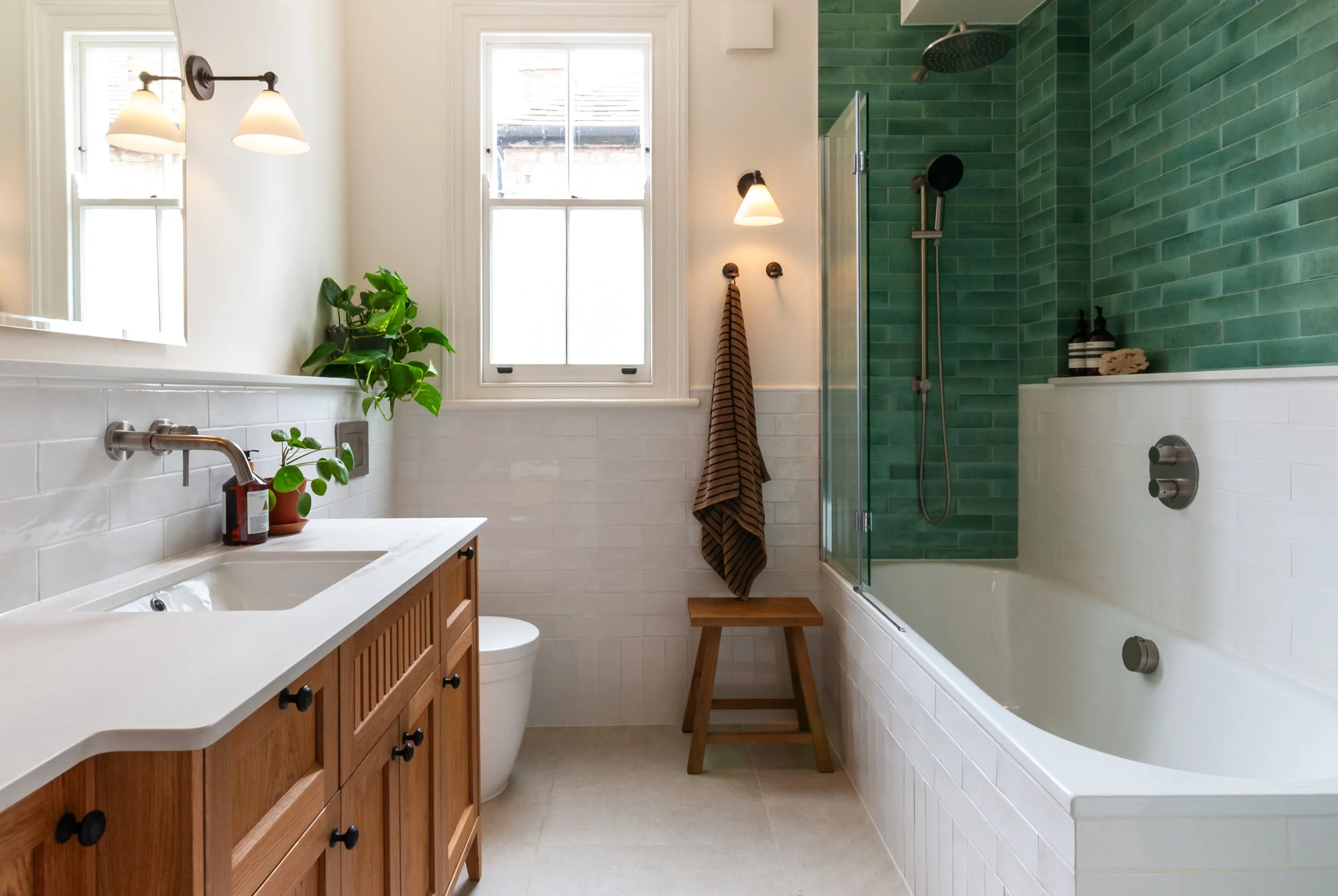 Family bathroom with oak vanity, white tiles and green tiled wall in Dulwich, South EastLondon