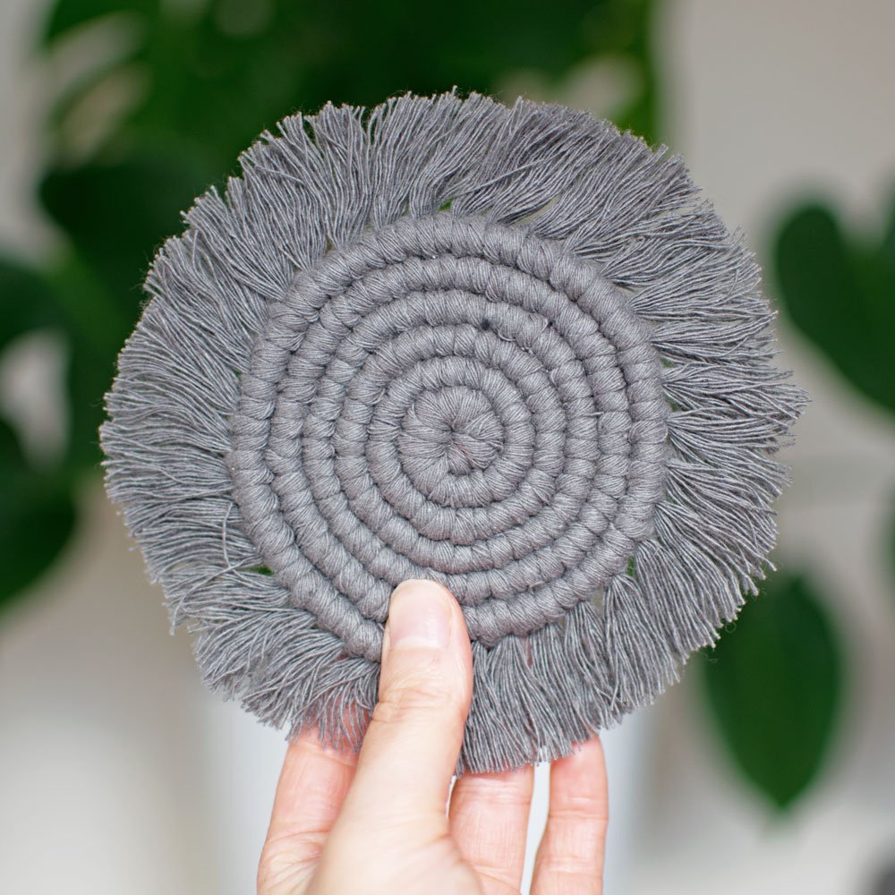 holding a grey macrame coaster