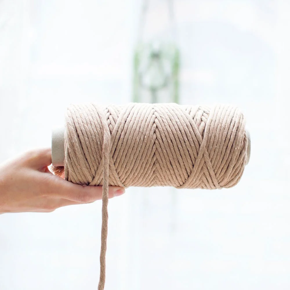 holding beige macrame cord spool