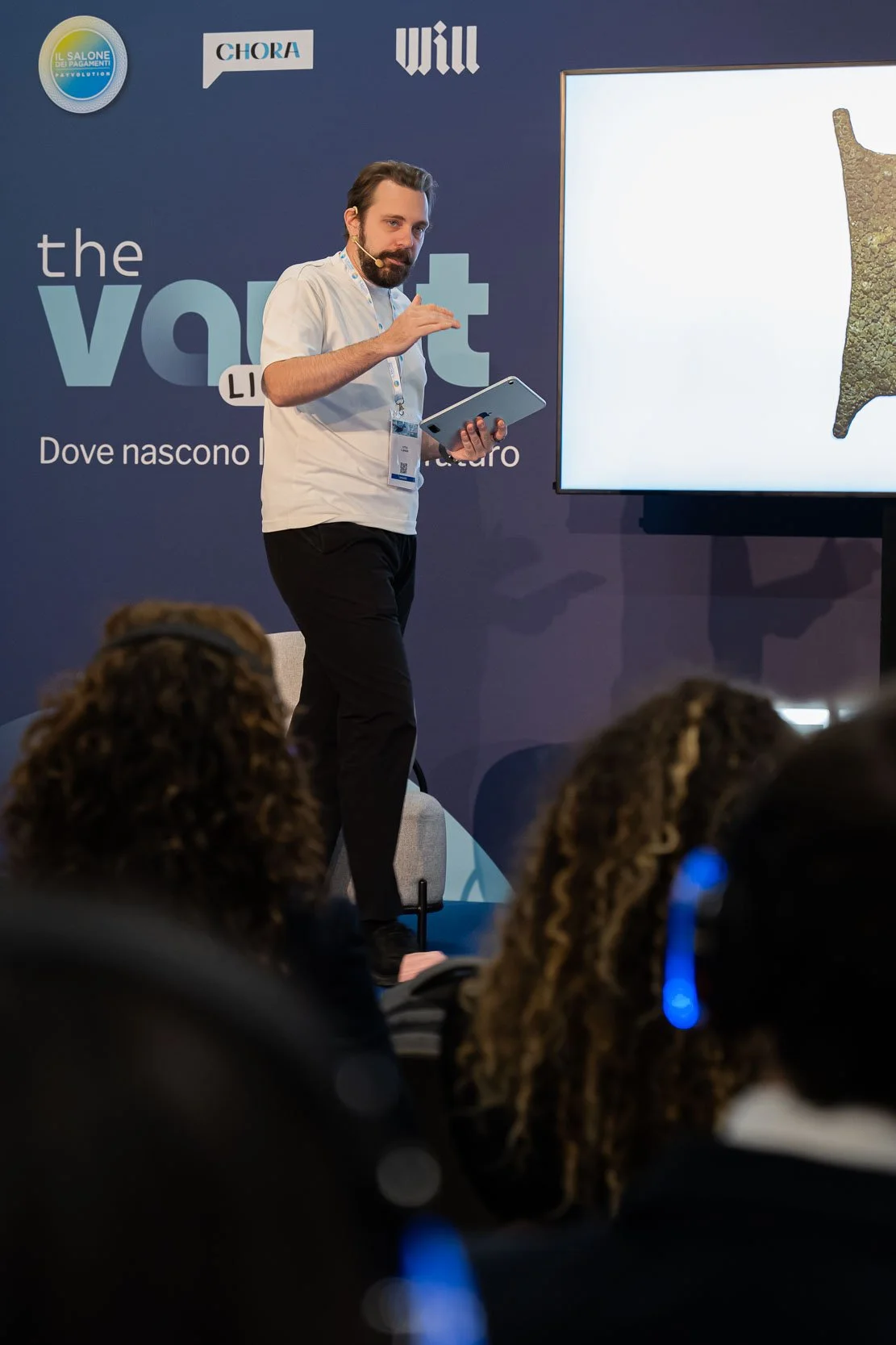 Relatore sul palco durante una sessione di The Vault Live al MiCo di Milano con il pubblico in ascolto tramite cuffie wireless, reportage fotografico dell’evento per Will Media e Chora Media
