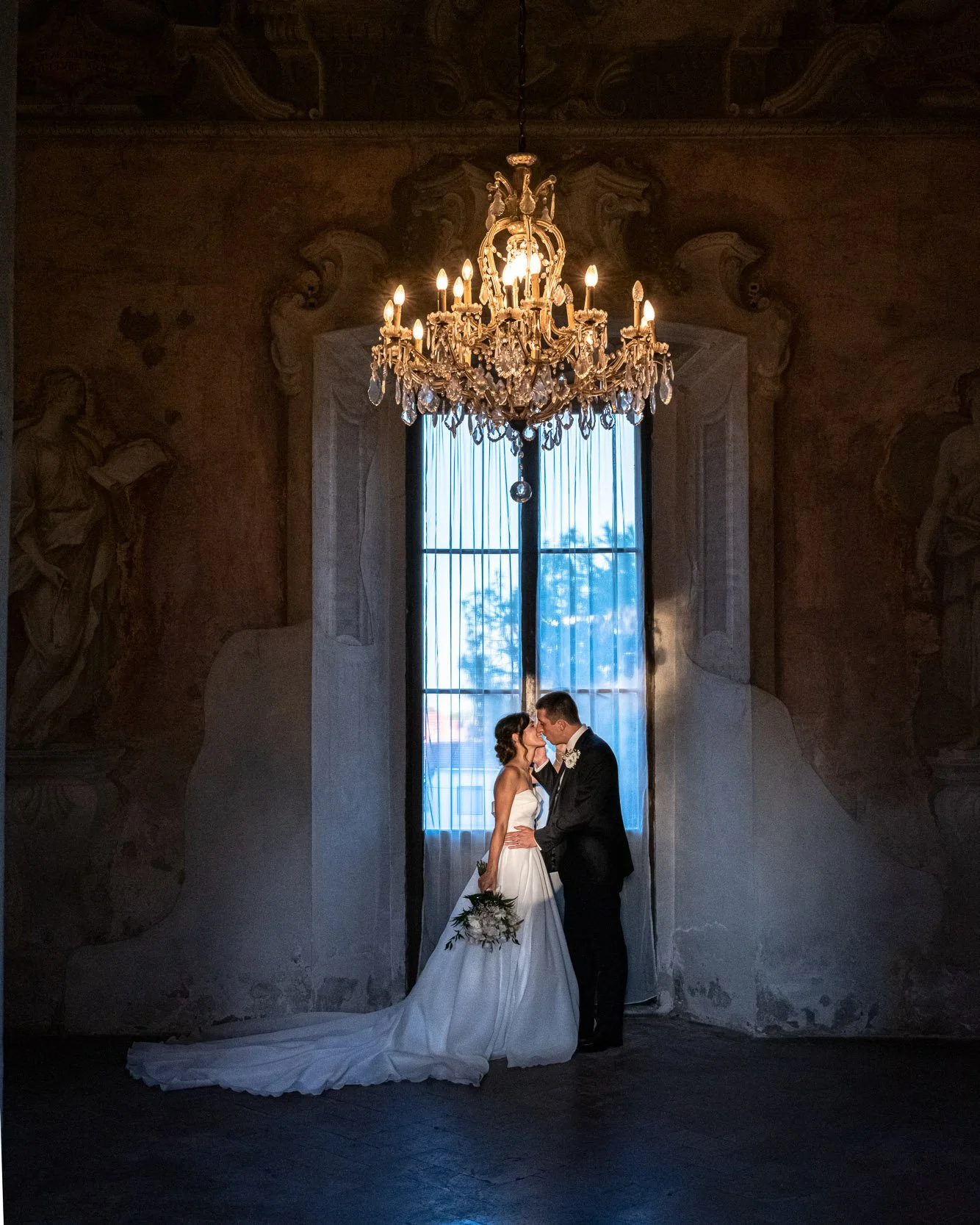 sposi che si baciano sotto un lampadario a villa resta mari fotografo matrimonio vittuone milano sud max capuzzi fotografo