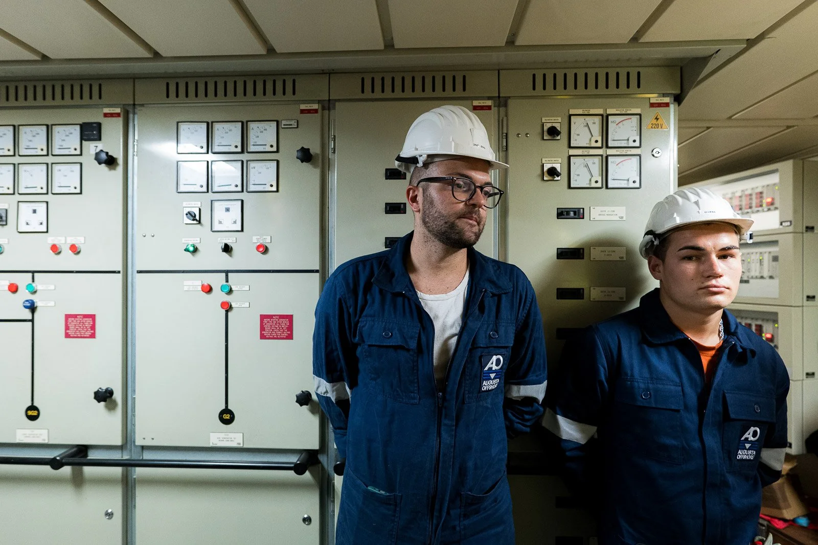 Due operatori con tute blu e caschi bianchi davanti ai quadri elettrici a bordo dell’Asso Ventiquattro.