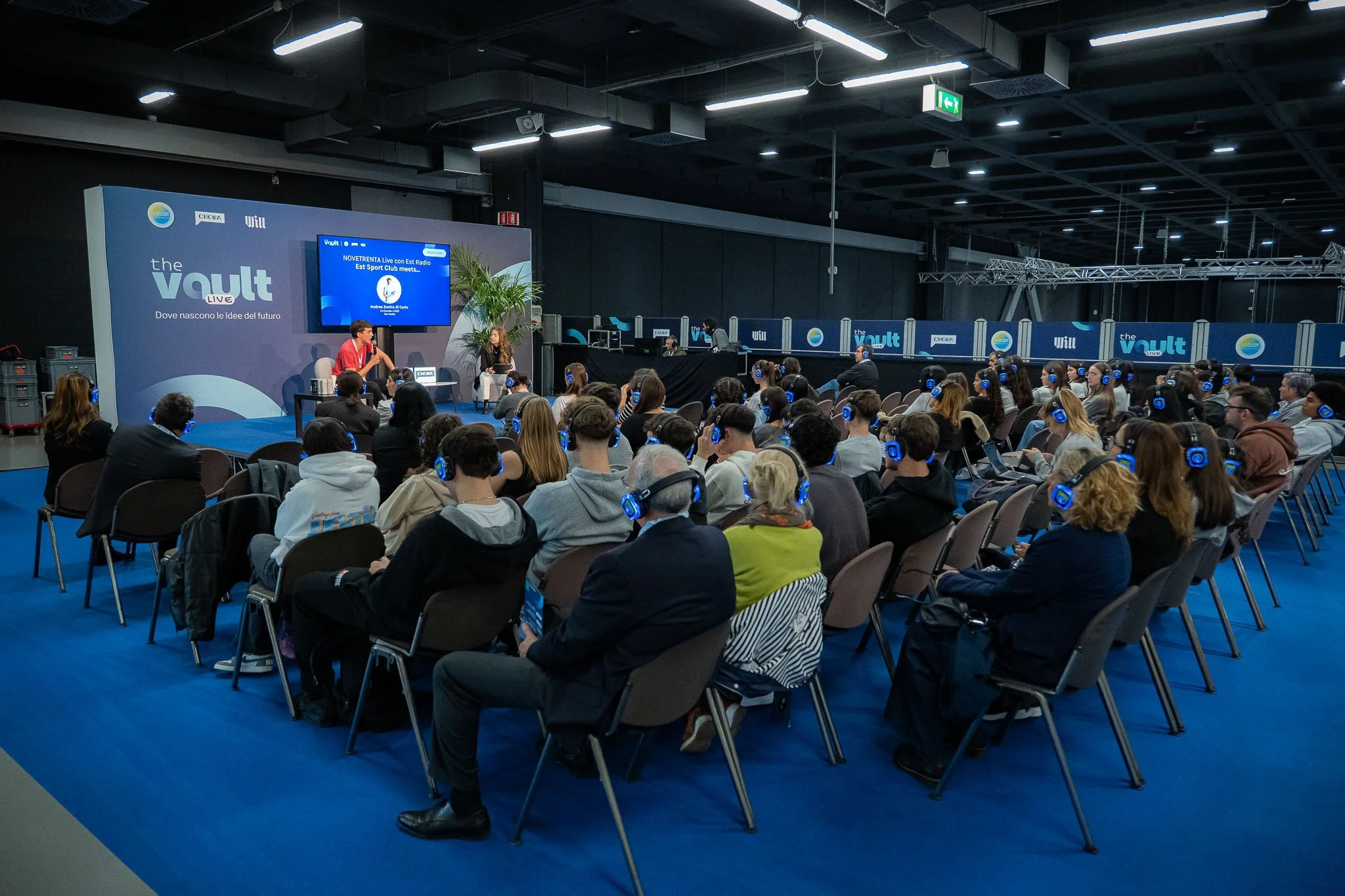 Vista d’insieme del pubblico durante una sessione di The Vault al MiCo di Milano, con partecipanti all’ascolto tramite cuffie silent conference. Reportage fotografico corporate realizzato per Will Media e Chora Media da Max Capuzzi.