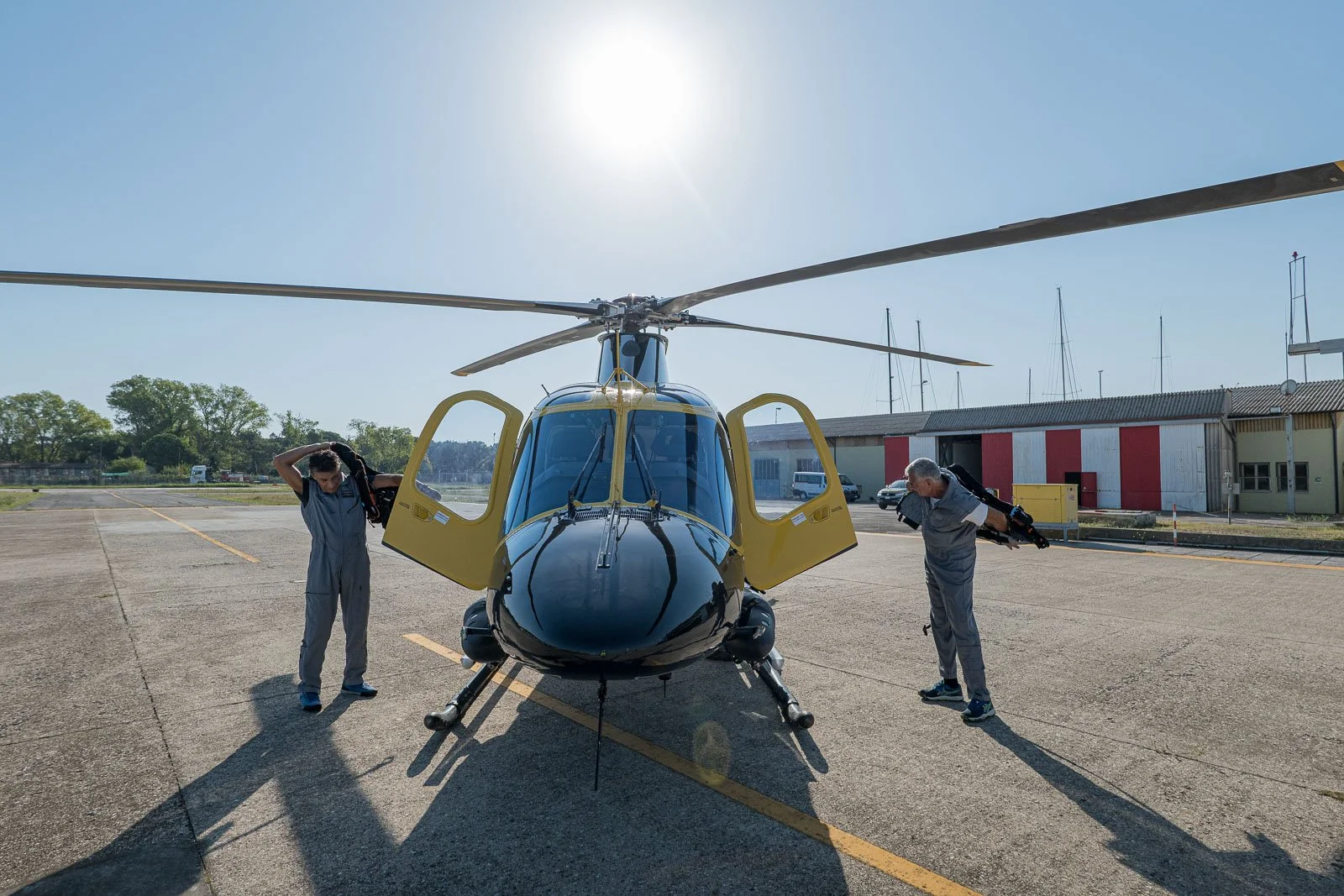 Due membri dell’equipaggio indossano i giubbotti salvagente accanto all’elicottero con le porte aperte.