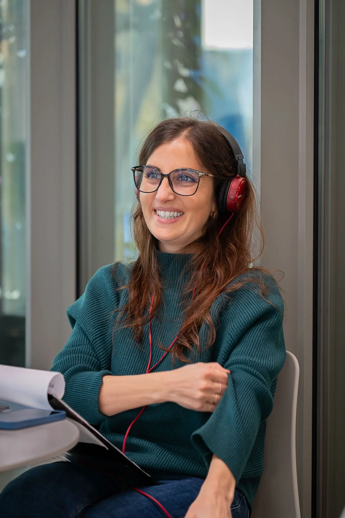 Tecnica al lavoro durante il backstage del podcast Unipol negli uffici aziendali di Milano, con cuffie e appunti per la produzione.
