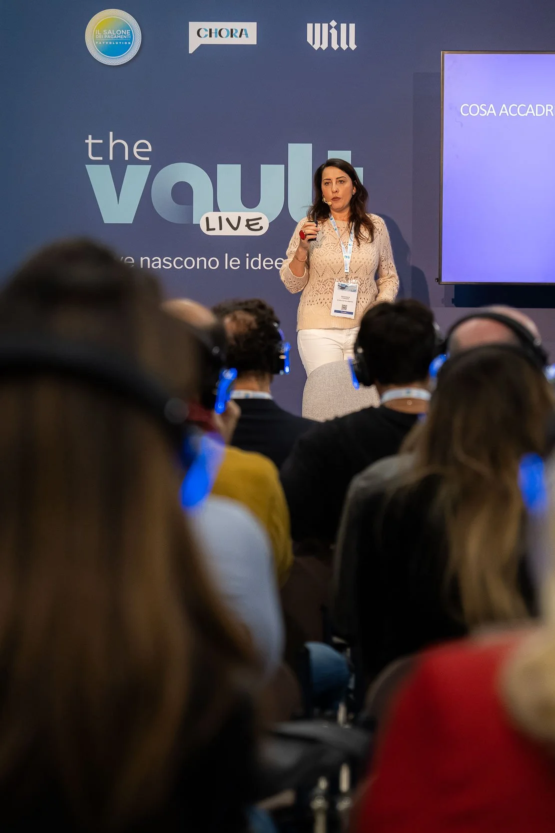 Relatrice sul palco durante una sessione di The Vault Live al MiCo di Milano, organizzato da Will Media e Chora Media, con pubblico in ascolto tramite cuffie
