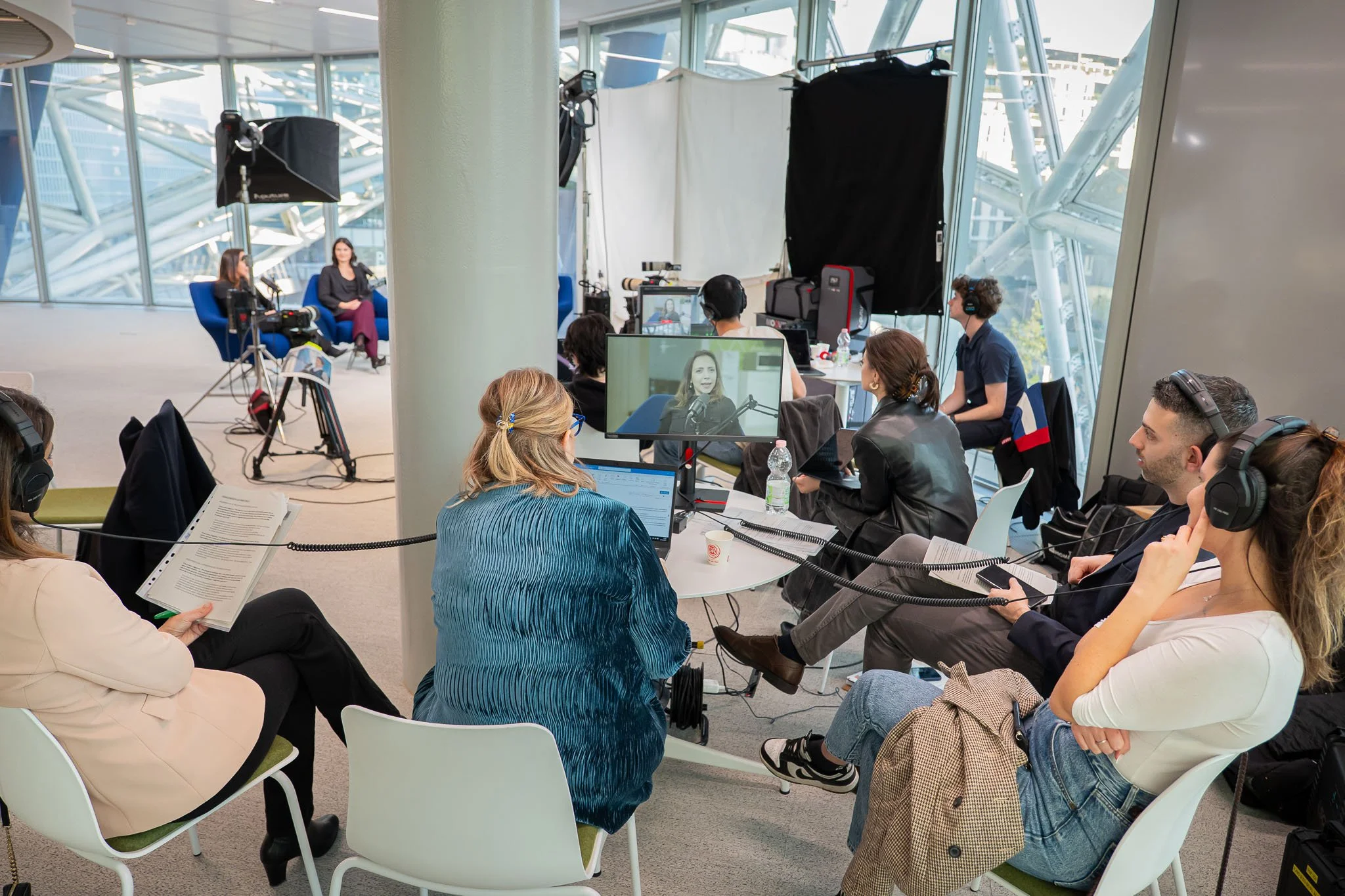 Vista d’insieme del set di produzione del podcast Unipol negli uffici aziendali di Milano, con il team al lavoro tra regia, monitor e tecnici audio.
