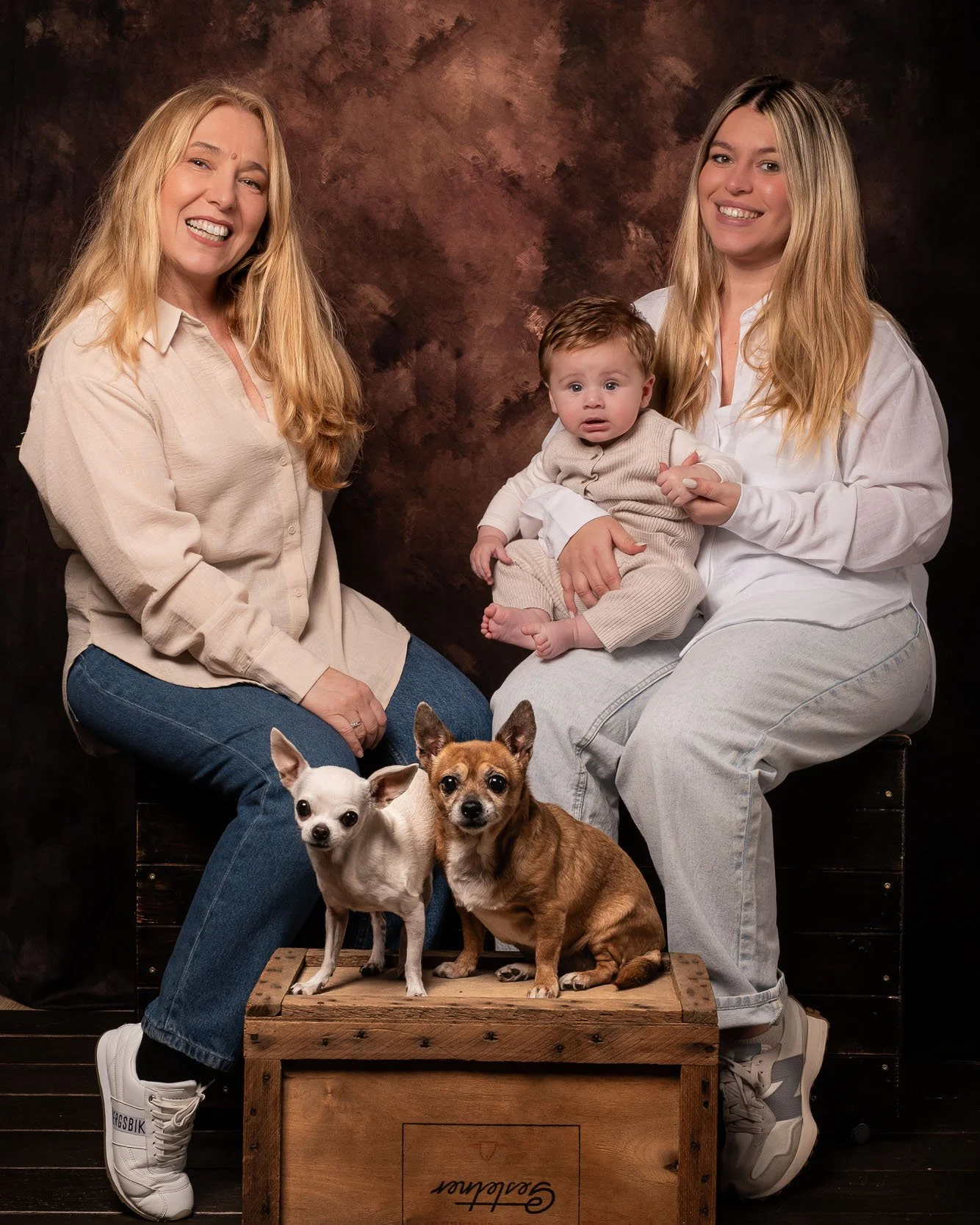 Ritratto di famiglia in studio con due donne, un bambino e due cani su sfondo artistico – servizio fotografico professionale a Buccinasco, Milano Sud.