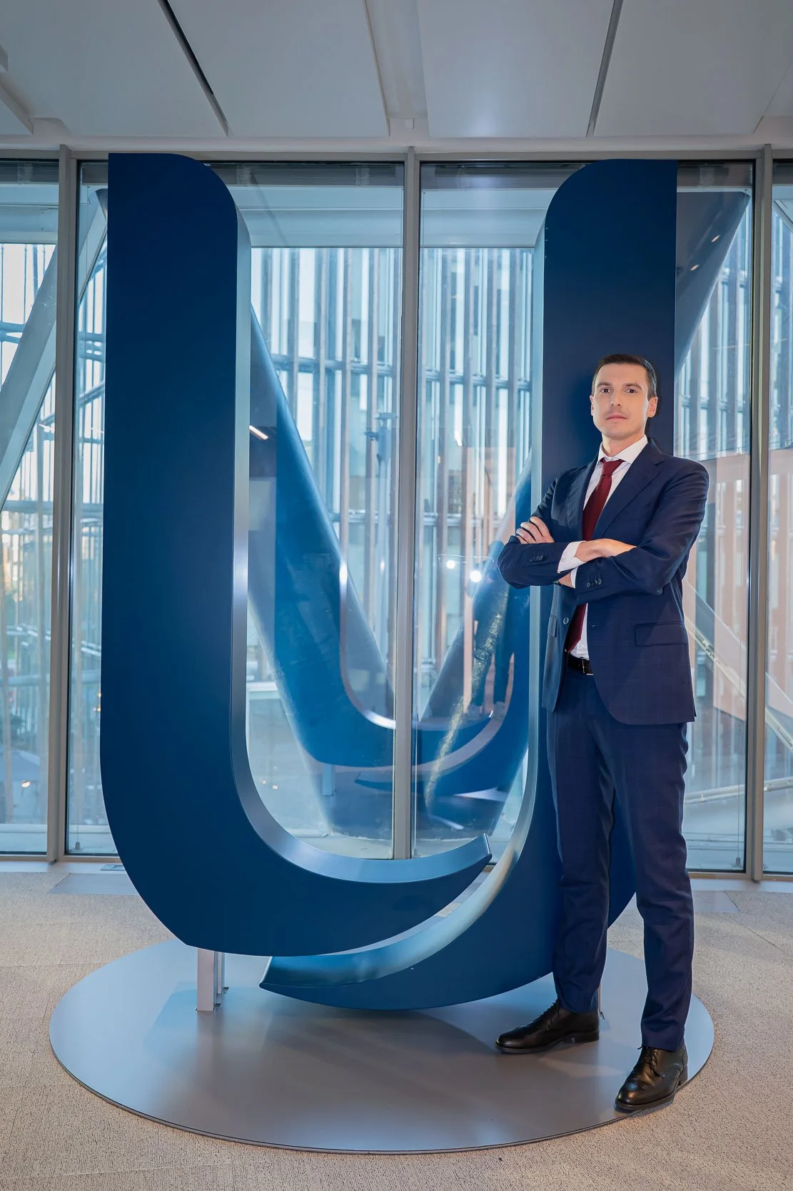 Ritratto corporate negli uffici Unipol di Milano, con il soggetto posato davanti al grande logo aziendale prima della registrazione del podcast.
