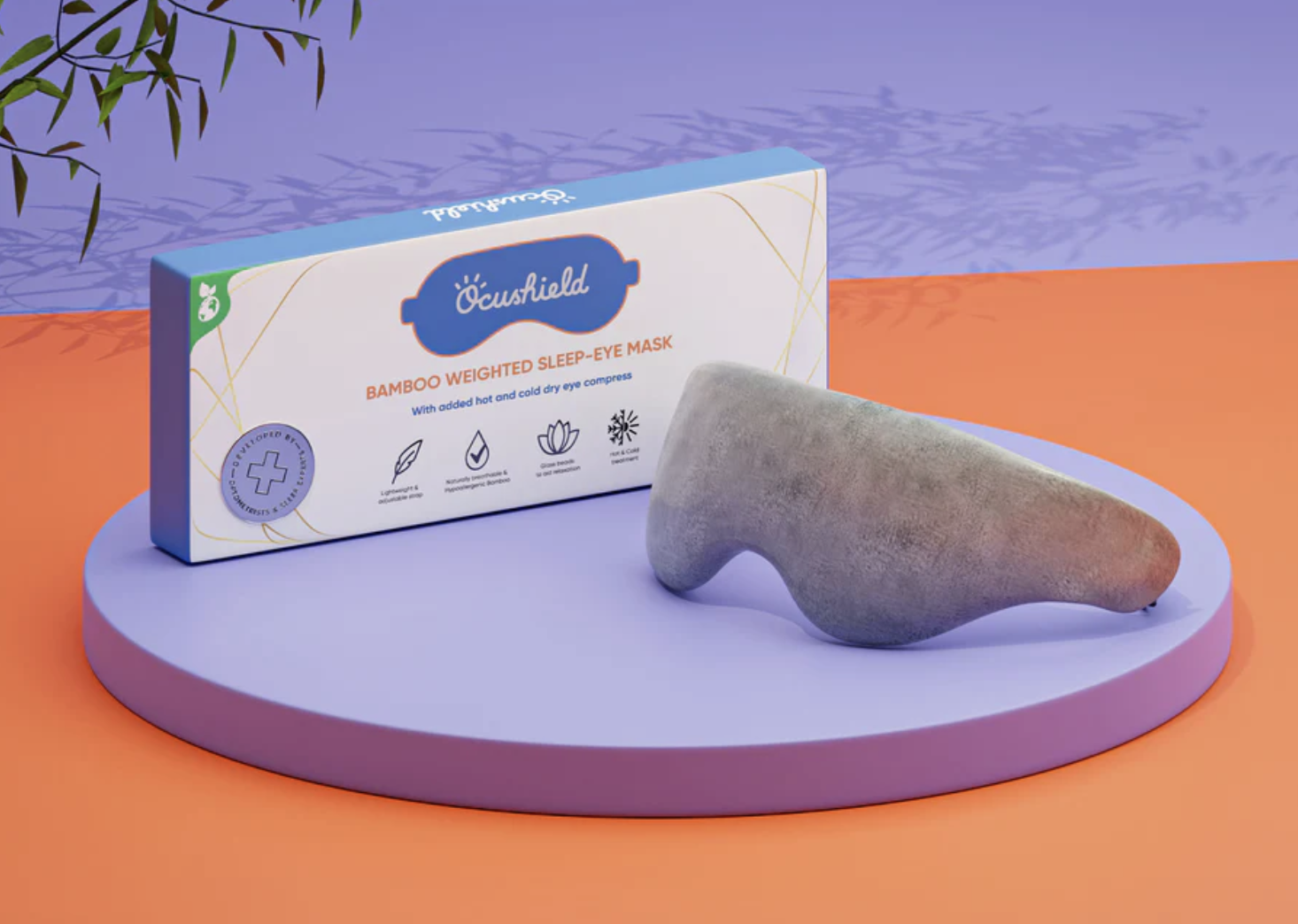 Bamboo weighted sleep-eye mask packaging on purple platform against an orange backdrop.