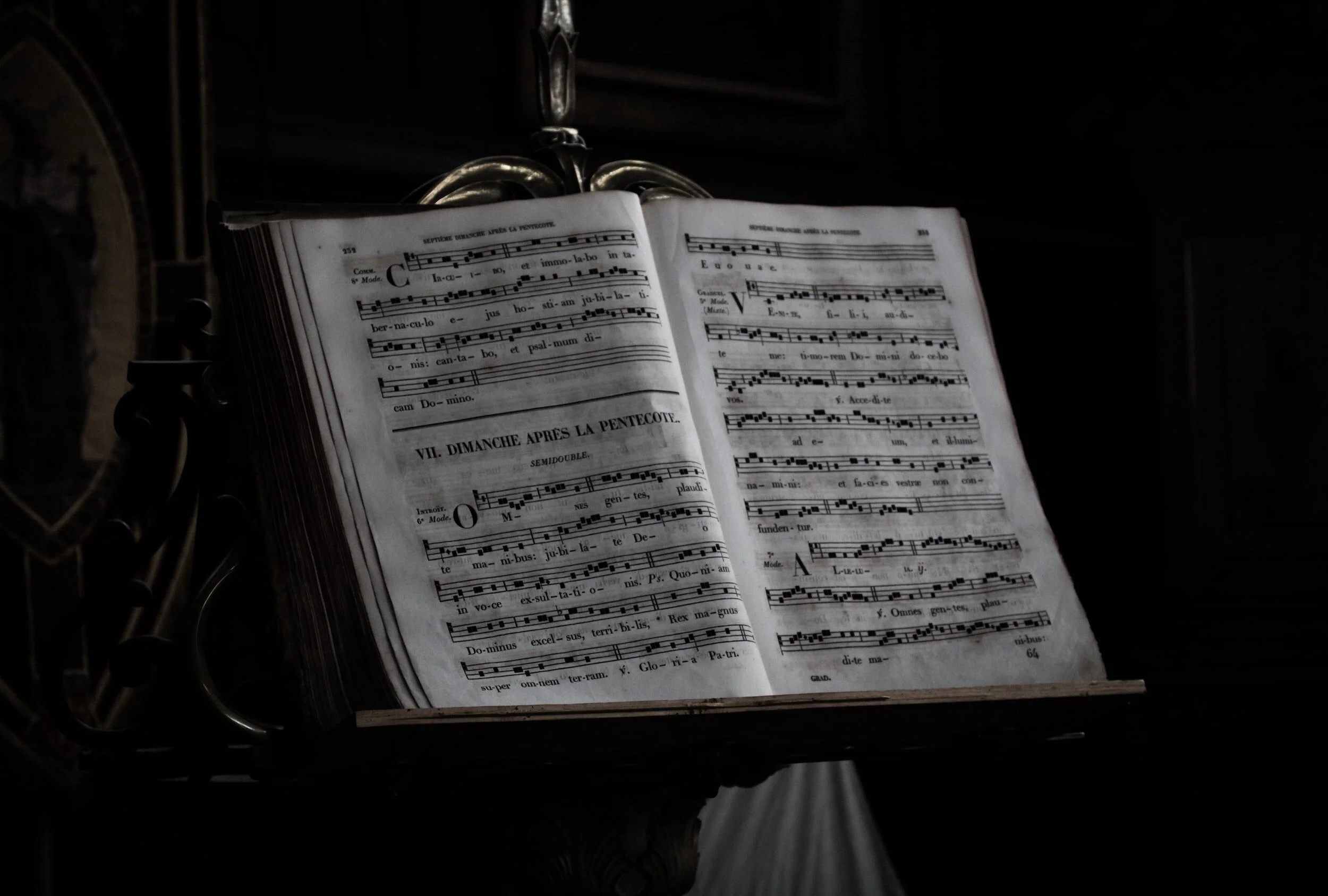 Open music book with Gregorian chant notation on dark, ornate stand