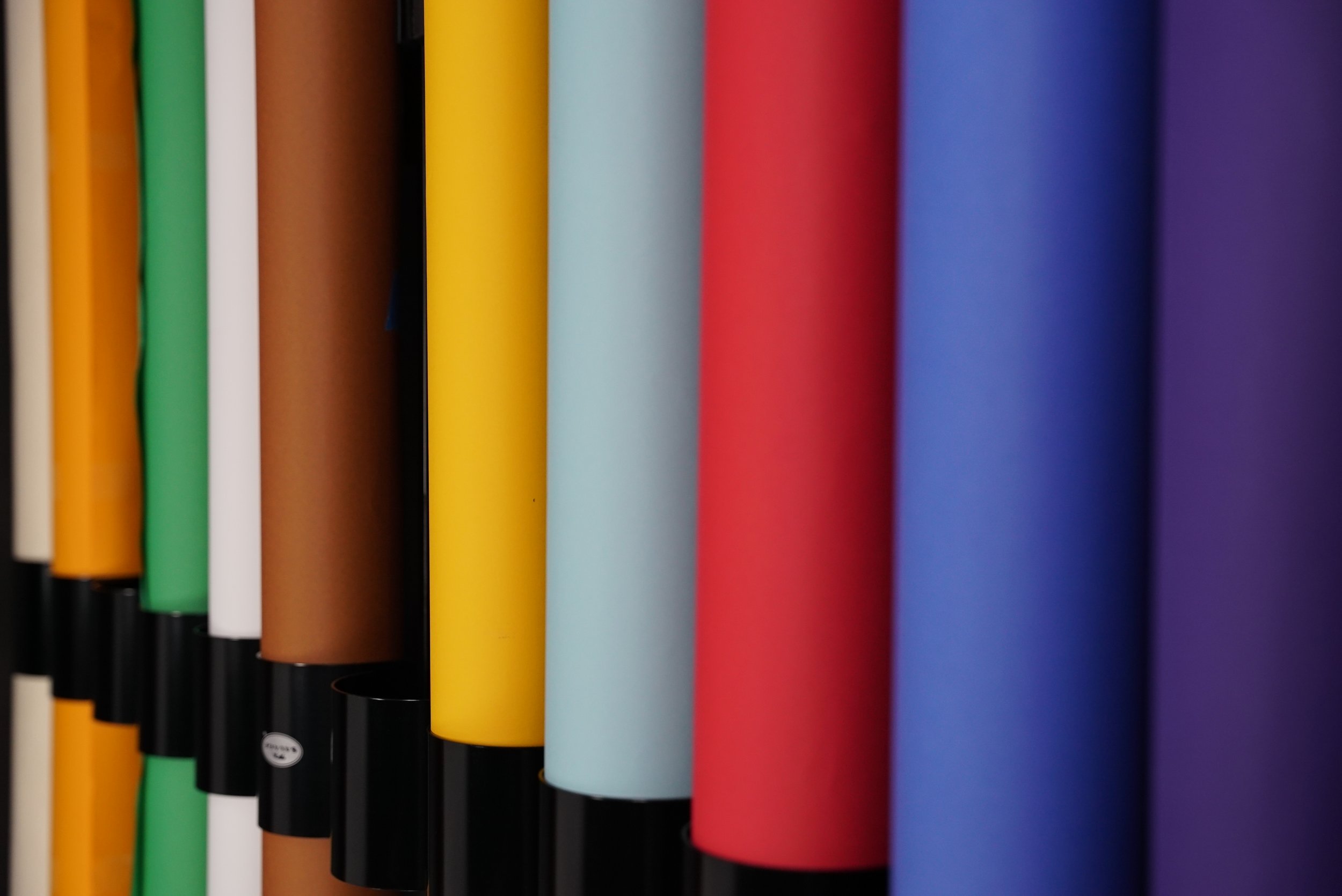 Close-up of colorful rolled papers or posters in various colors including yellow, blue, red, purple, green, brown, white, and black.