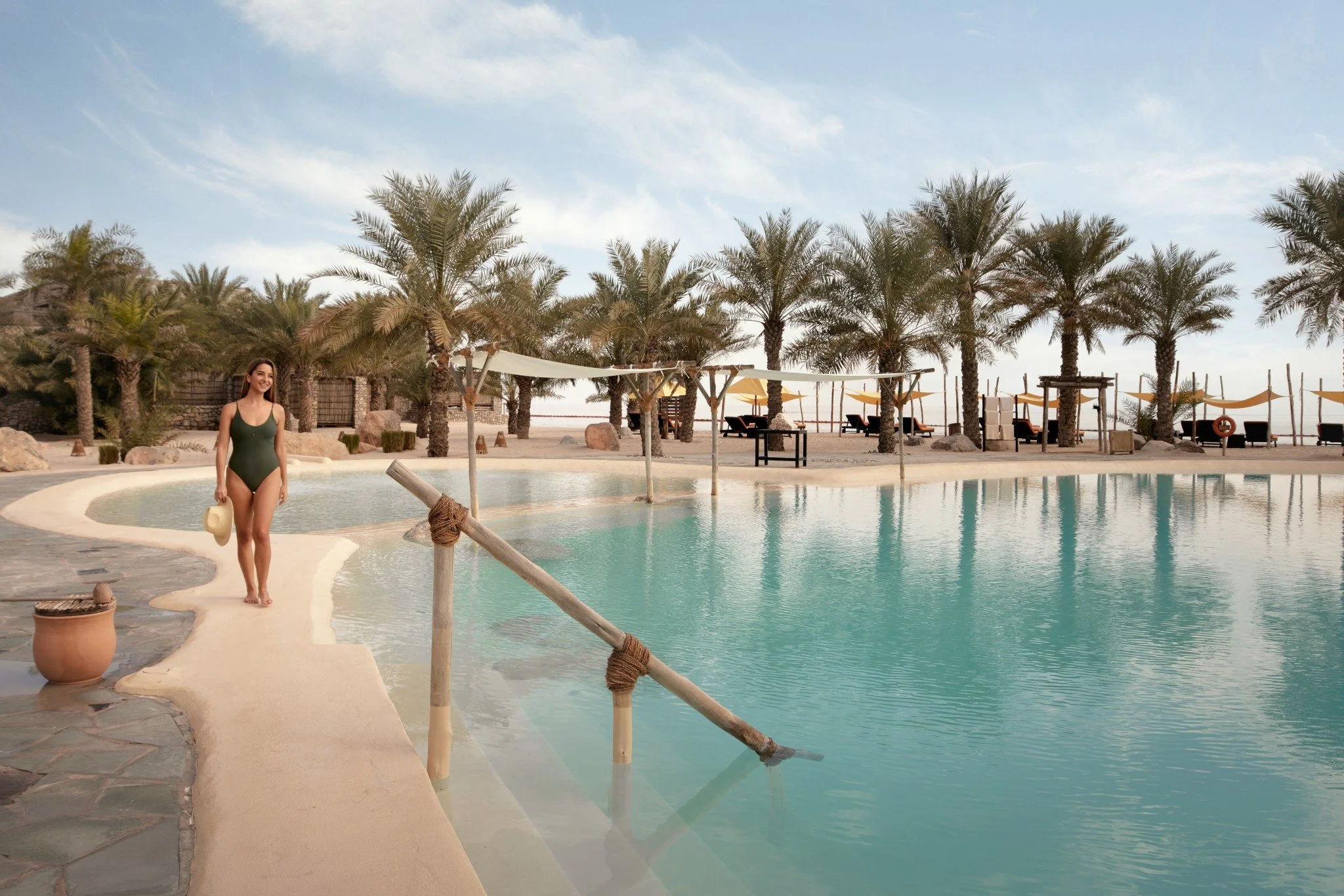 Woman walking by pool at Six Senses Zighy Bay
