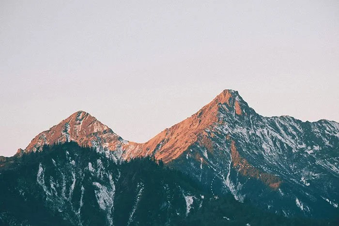 Two mountain peaks with a slight bit of snow in sunlight
